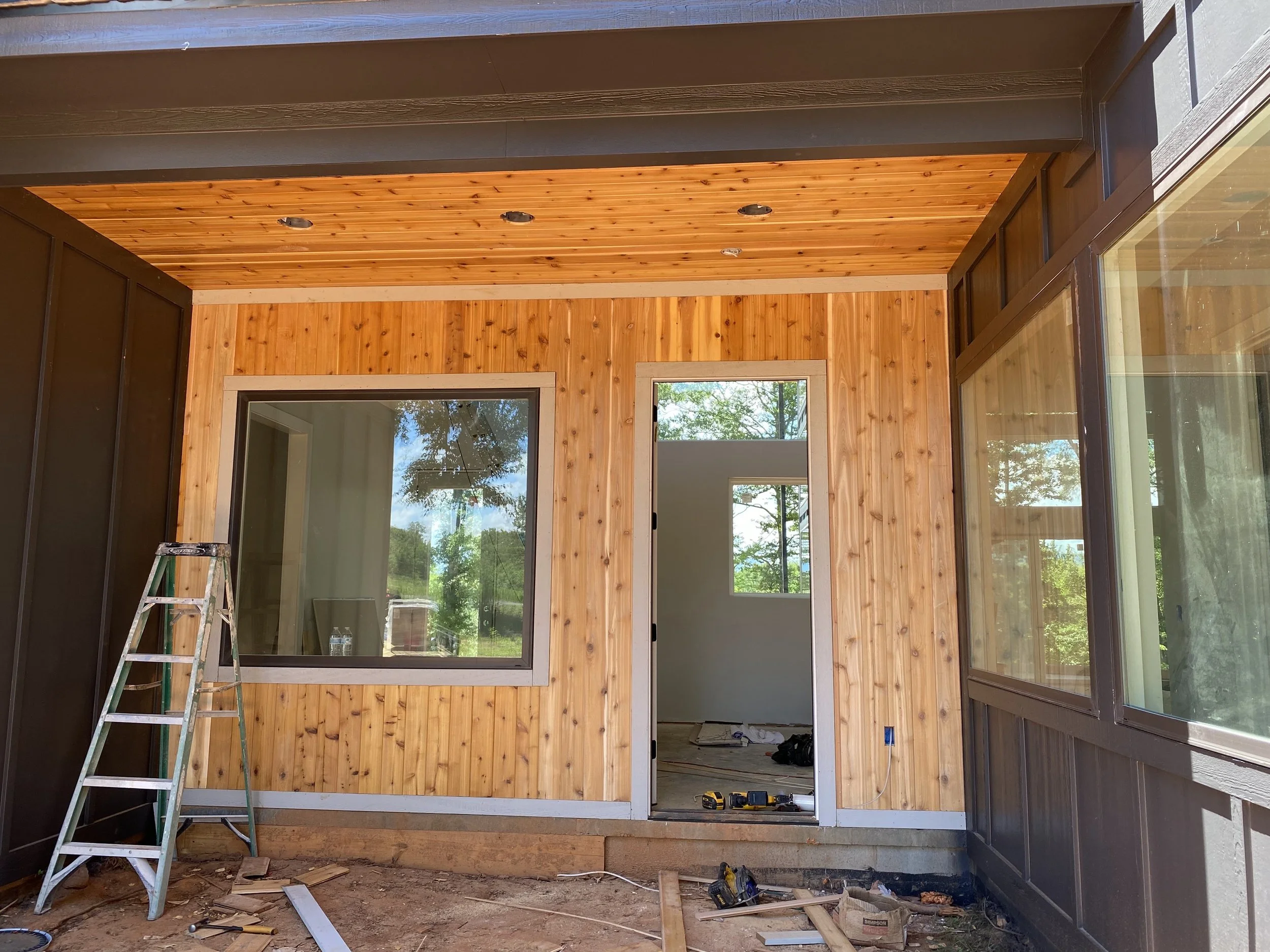 Fiber cement board and baton siding. 1x6 cedar tongue and groove installed on front entry wall and ceiling.