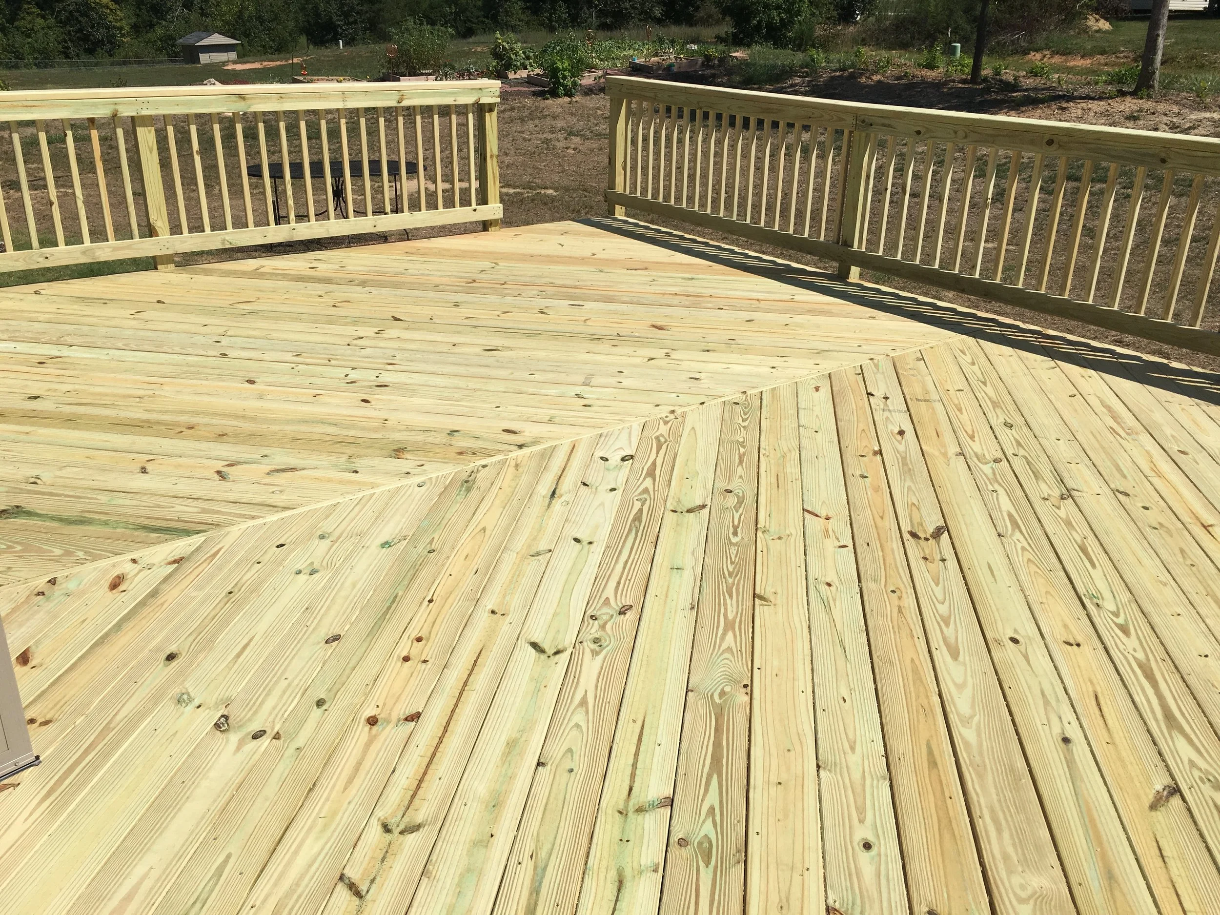Pressure treated wood deck with herringbone decking board pattern. Pressure treated wood handrails.