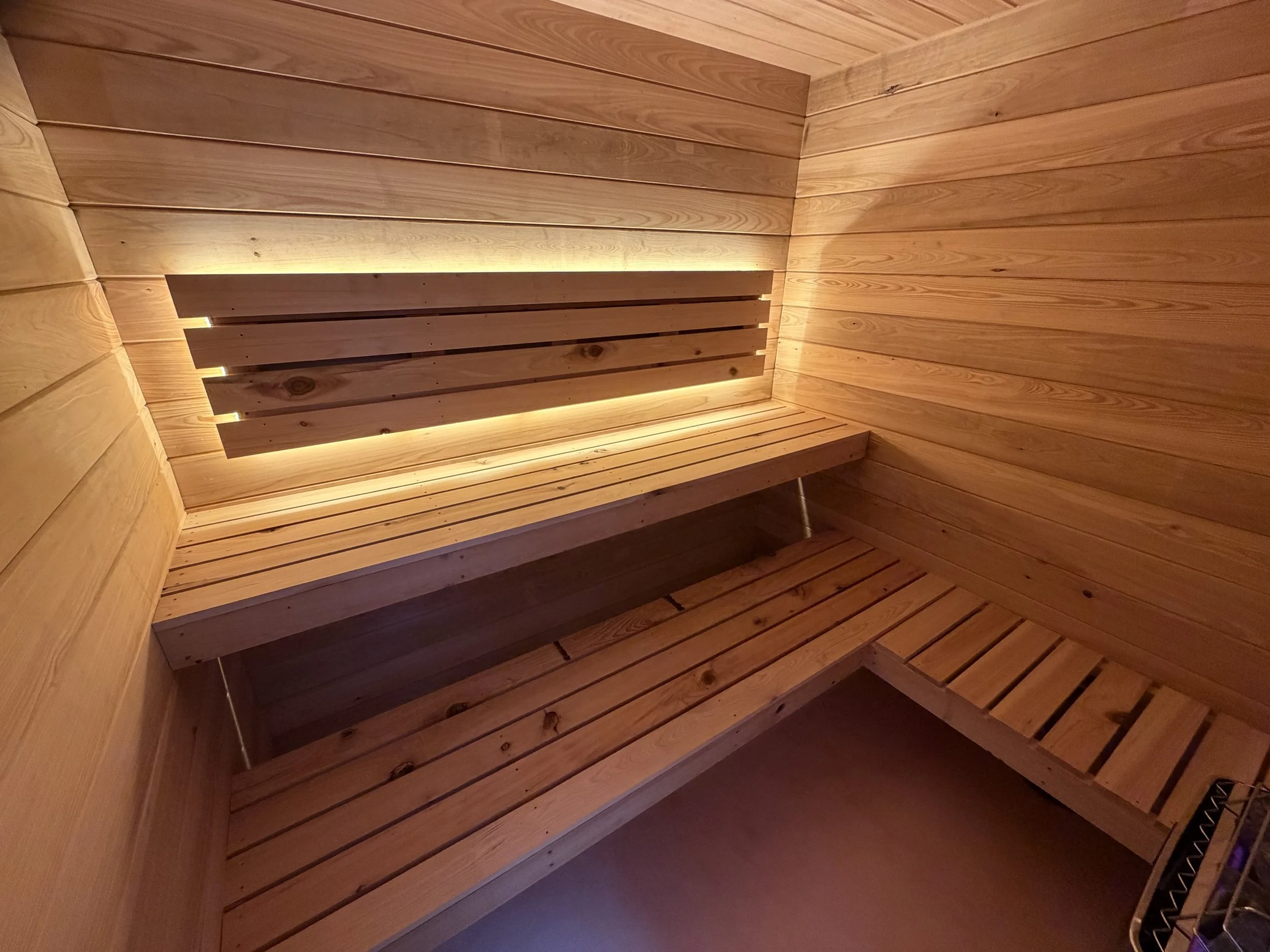 6'x7'x7' custom shower room with Harvia WiFi heater. Walls, ceiling, and benches are cypress wood. Floor is micro cement.