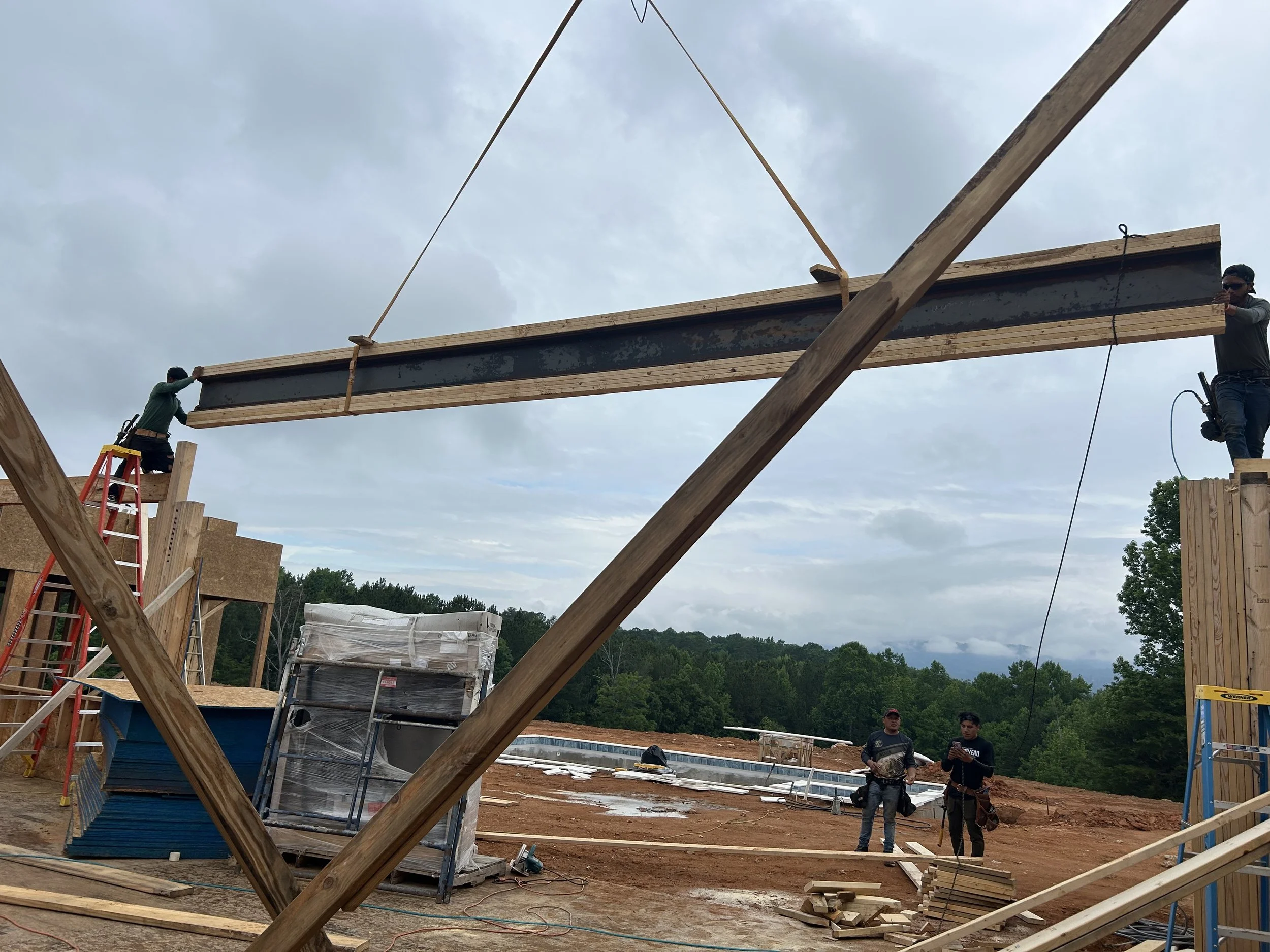 Custom steel beam with welded on plates built up with 2x6's on top and bottom set in place with crane for future 30'x10' sliding door.