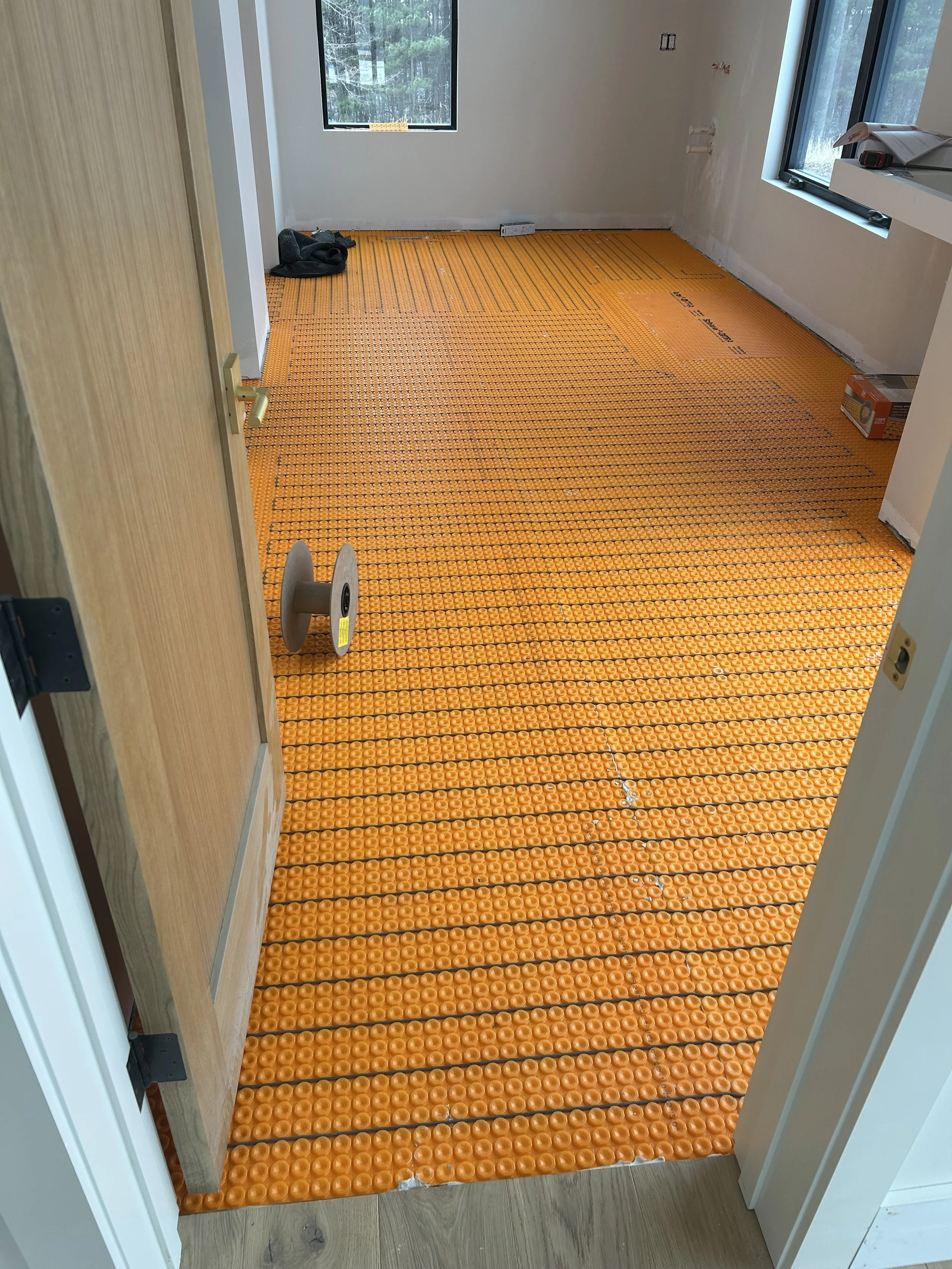Schluter Ditra Heat tile underlayment installed before tile in the primary bathroom. Schluter Ditra Heat wire and equipment run to heat tile floor.