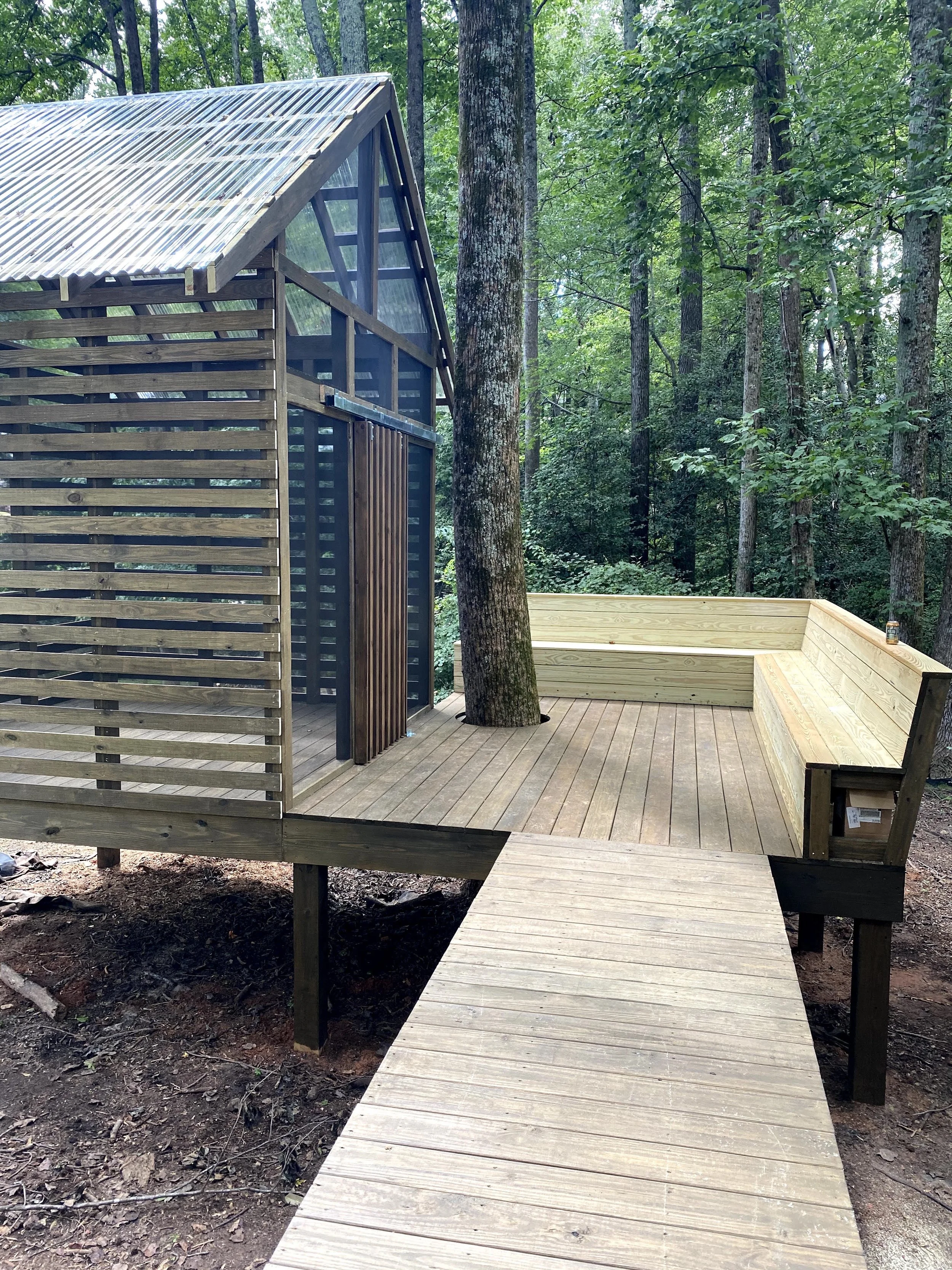 Custom tree house with open wood deck and angled back benches.