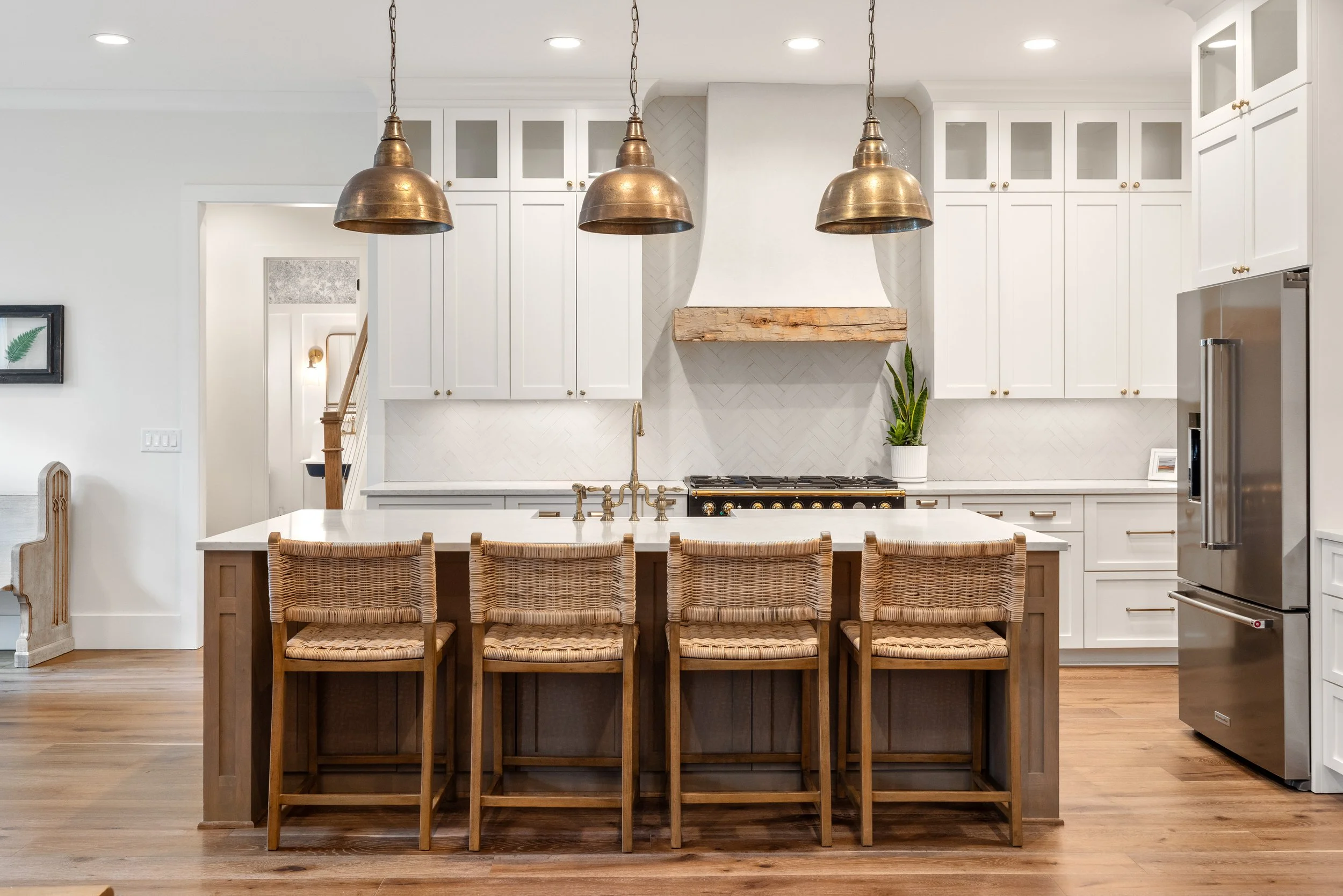 Custom cabinetry. Custom site built arched stucco coated hood vent with reclaimed wood detail. Quartz counters with tile backsplash installed on herringbone pattern.