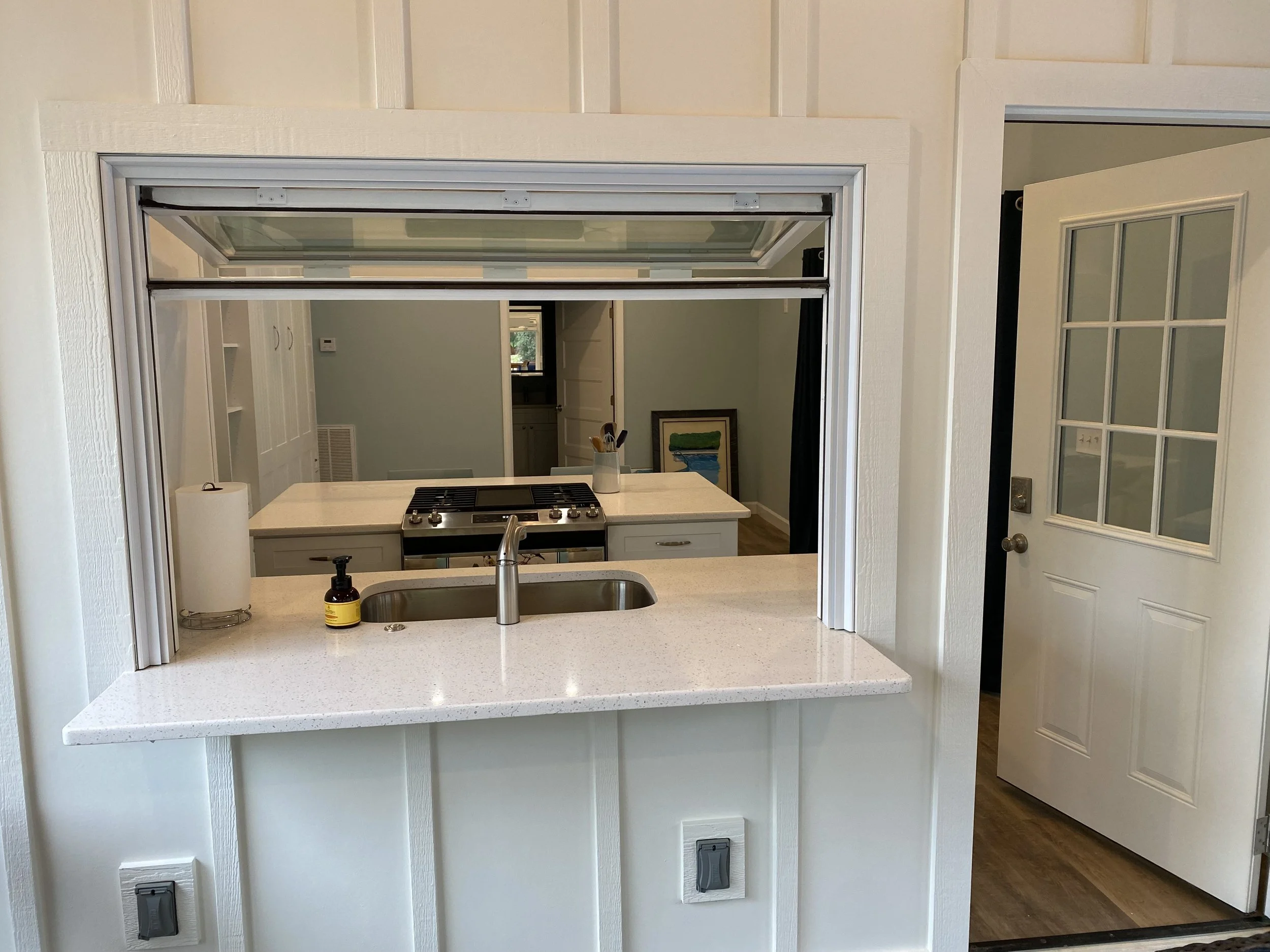Kitchen of detached pool house/studio apartment. Fold up pass through window to screened in porch. Quartz counters. Fiber cement board and baton siding.