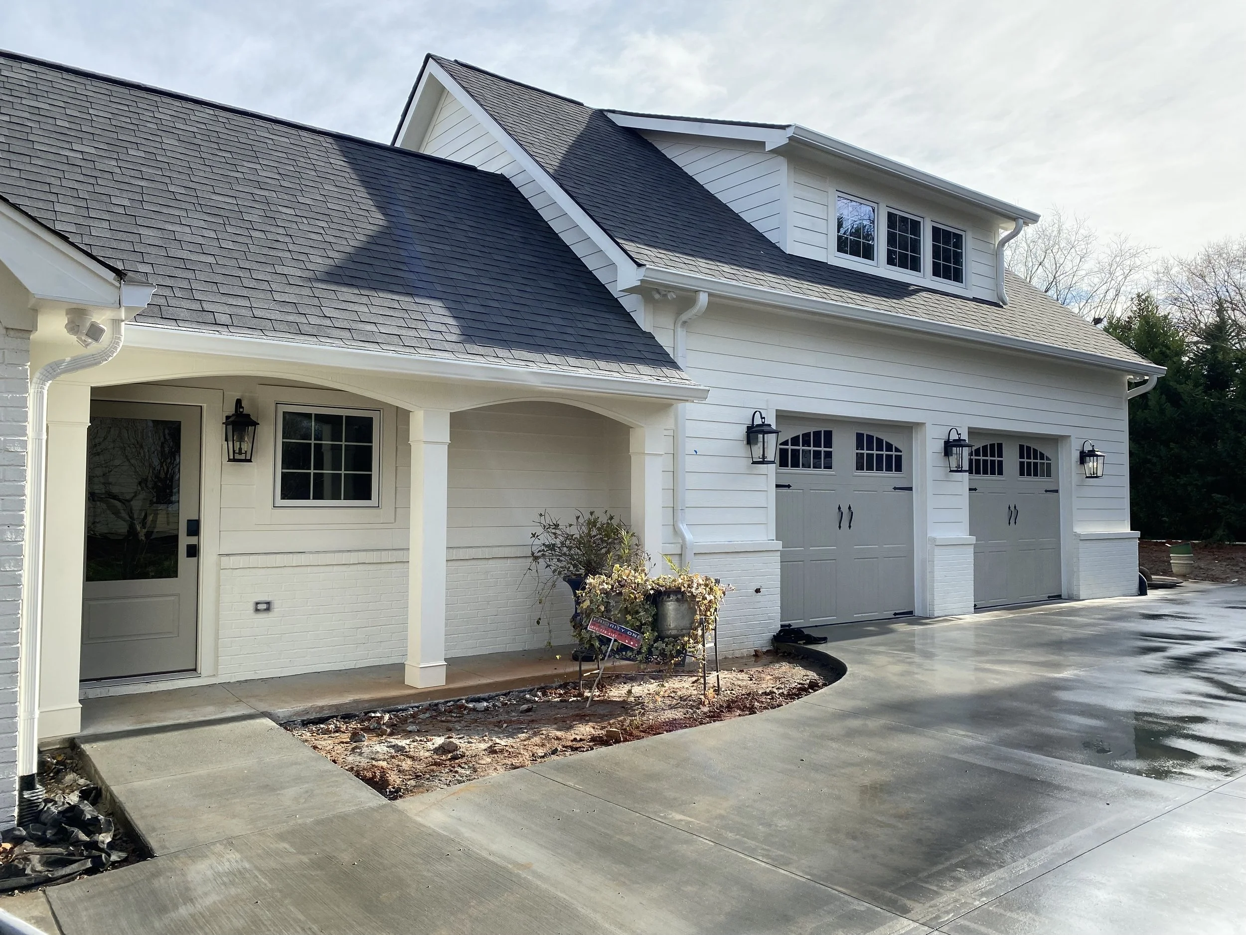 Attached garage with living space and home office above. Fiber cement siding. Carriage style 3 panel garage doors.