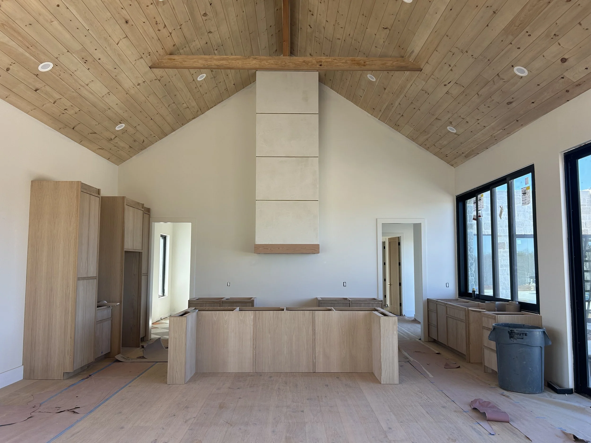 8" white oak engineered hardwood flooring. Custom white oak cabinetry. Custom hood vent covered in micro cement and white oak detail. Gold metal strips also added in hood vent for additional detail and interest. 12'x7' four panel sliding pass though 