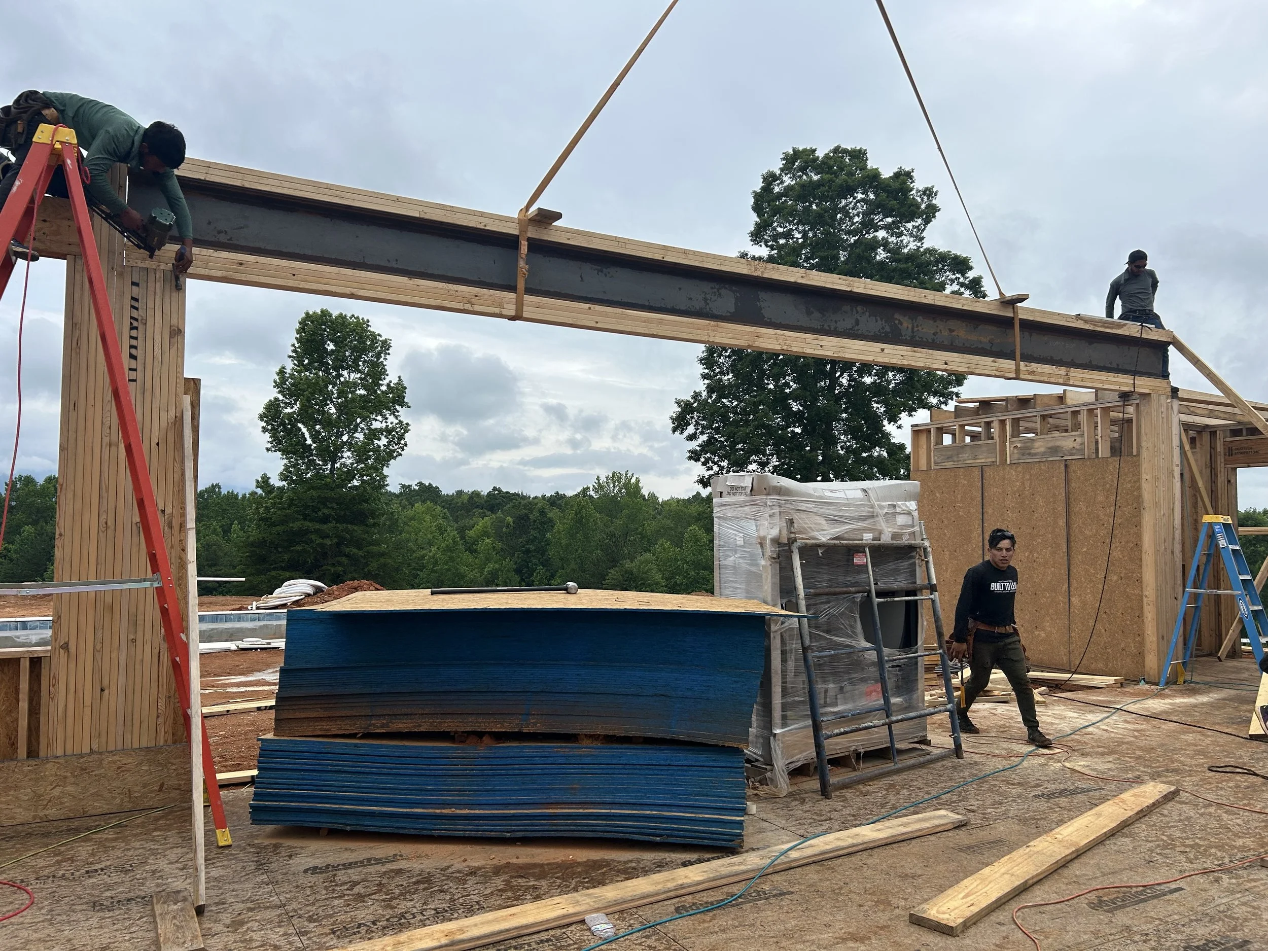Custom steel beam with welded on plates built up with 2x6's on top and bottom set in place with crane for future 30'x10' sliding door.