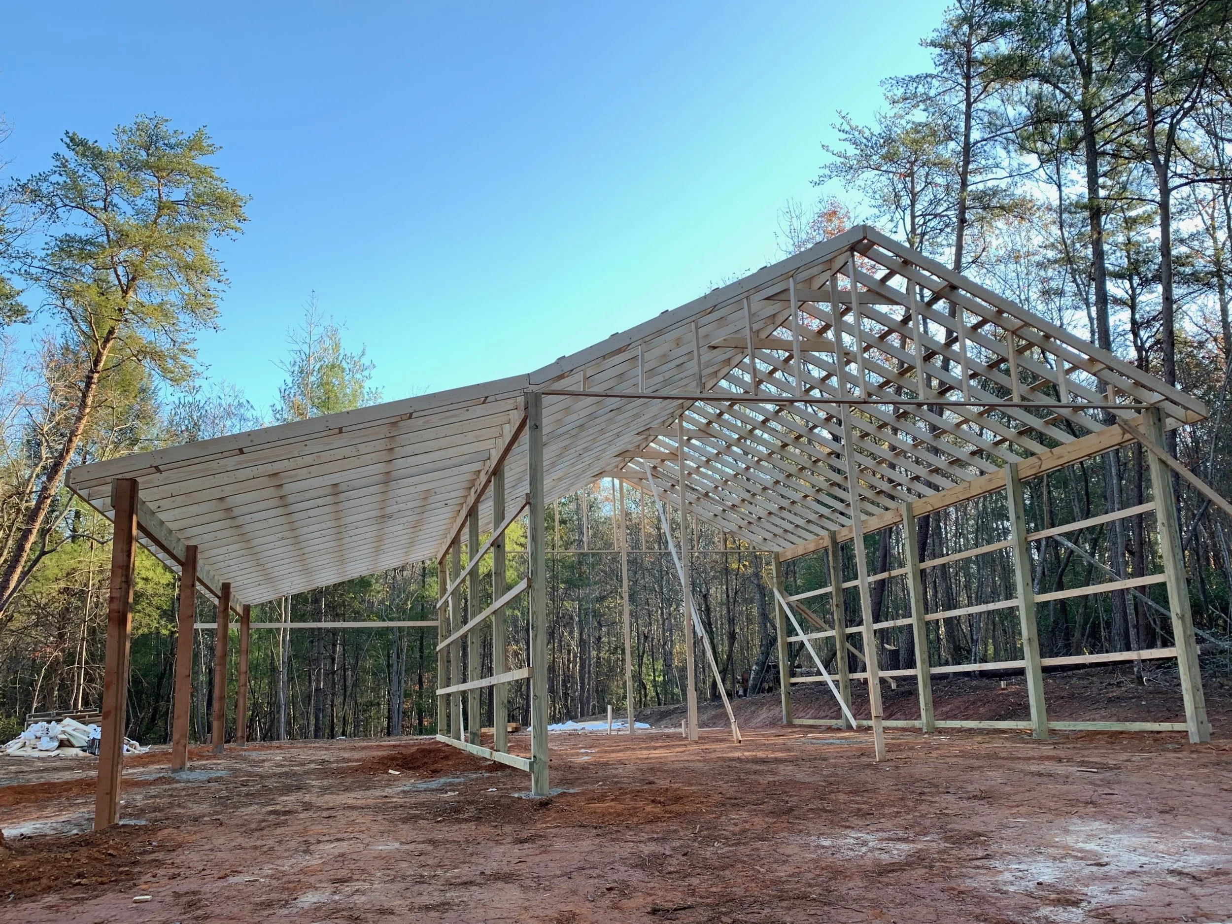 The beginning of the framing of a large pole barn with a lean to along one full side. 