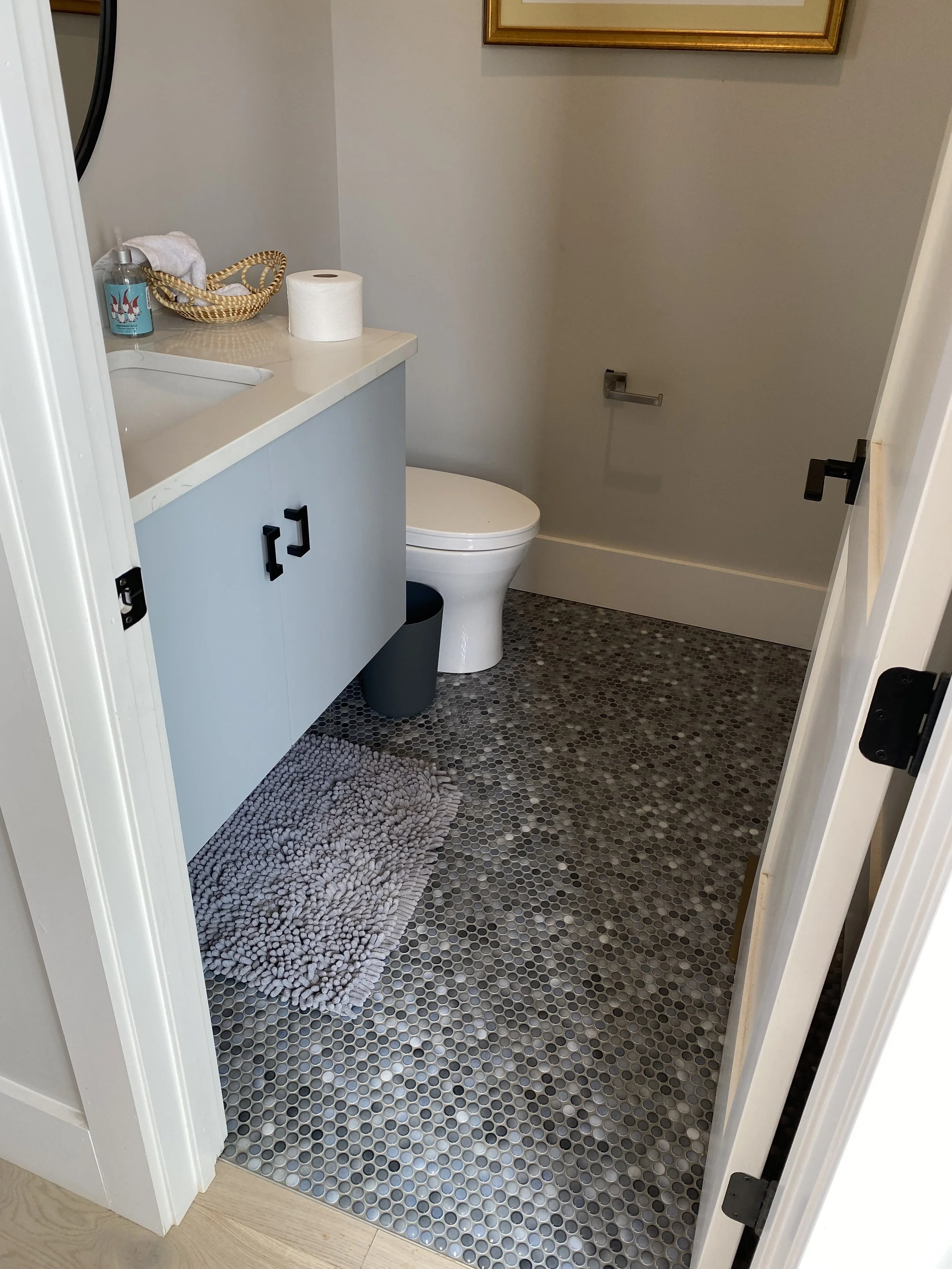 Custom floating vanity with Quartz top. Penny tile on floor.