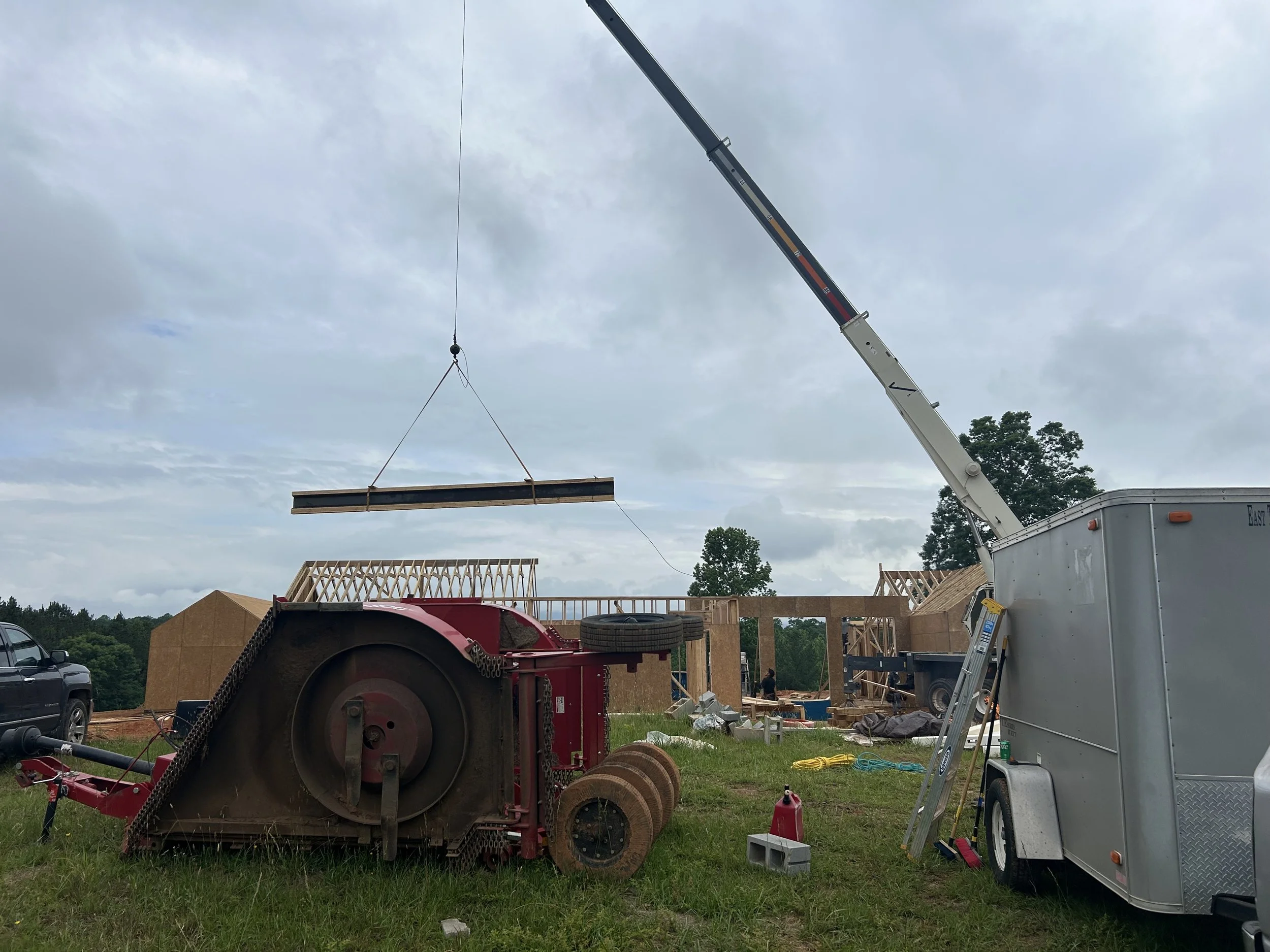 Custom steel beam with welded on plates built up with 2x6's on top and bottom set in place with crane for future 30'x10' sliding door.