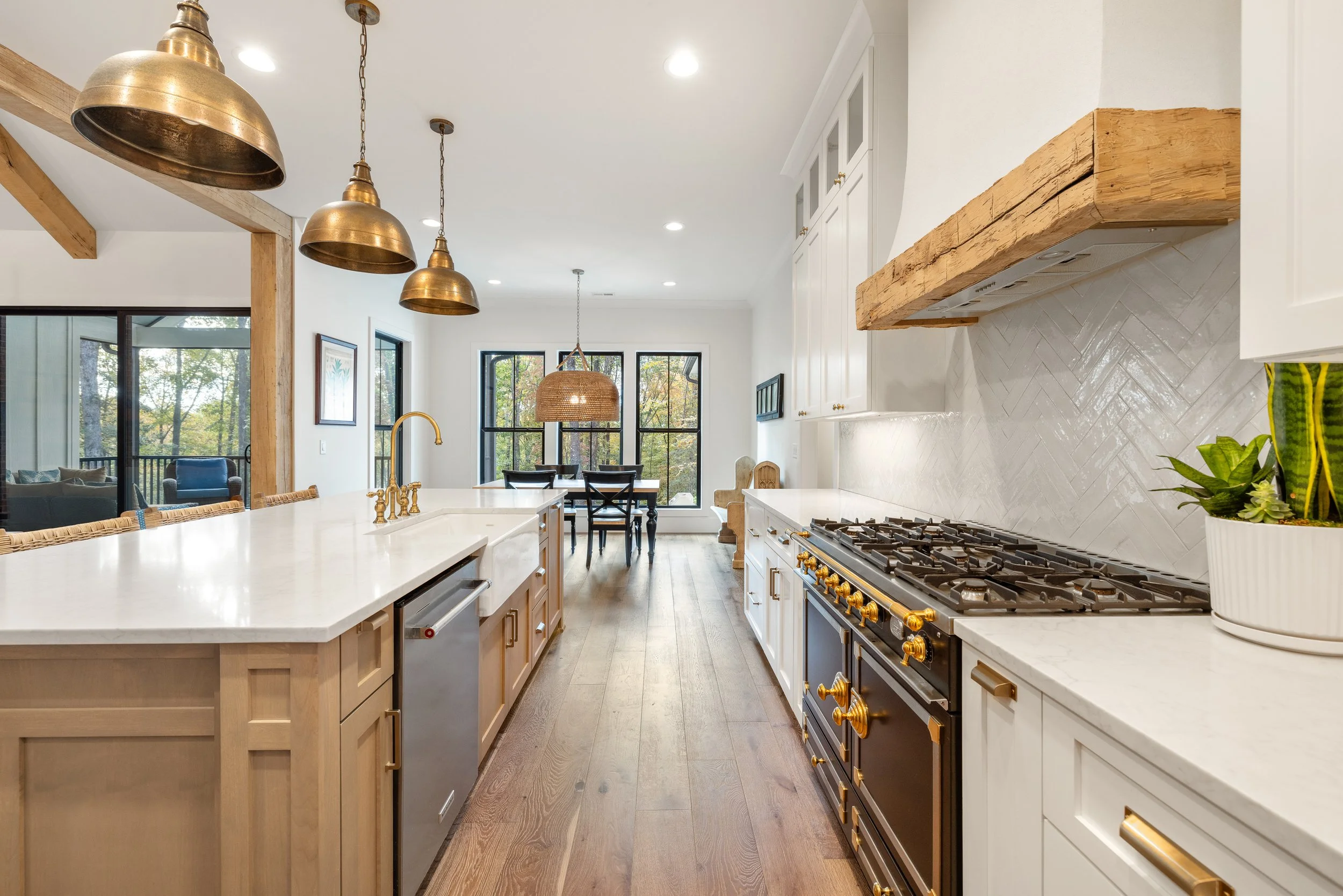 Custom cabinetry. Custom site built arched stucco coated hood vent with reclaimed wood detail. Quartz counters with tile backsplash installed on herringbone pattern.