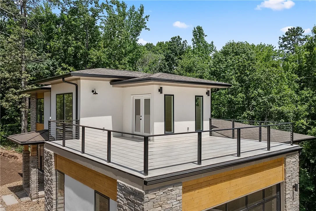 Sun deck above garage. Aluminum cable railing. Stucco, stone, and cedar siding.