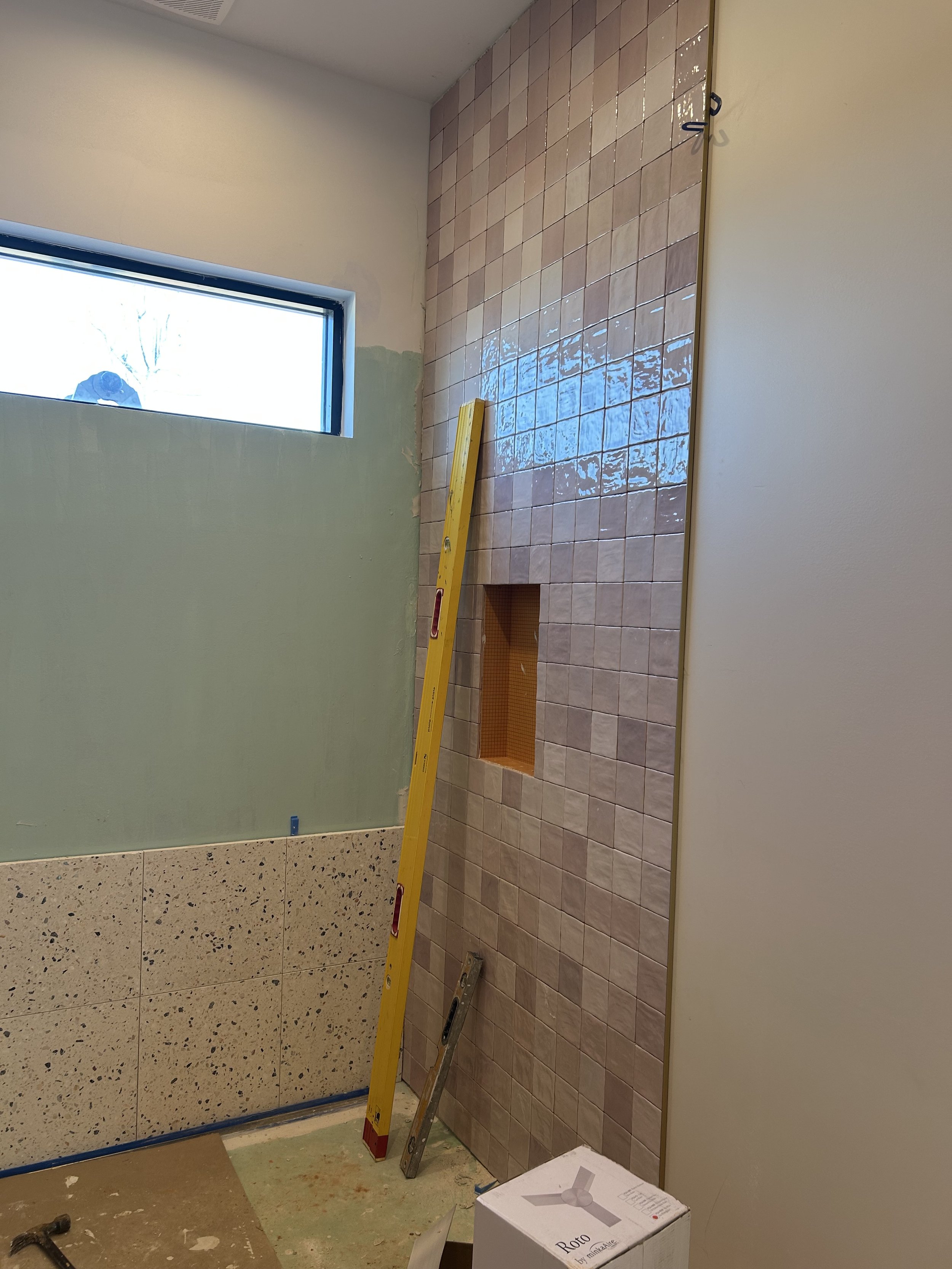 4x4 pink square tiles installed on bathroom wall to ceiling. 16"x16" real terrazzo tiles installed on floor and back wall of bathroom and shower.