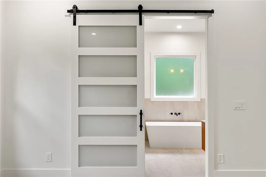8' Tall frosted glass sliding barn door leading to primary bathroom.
