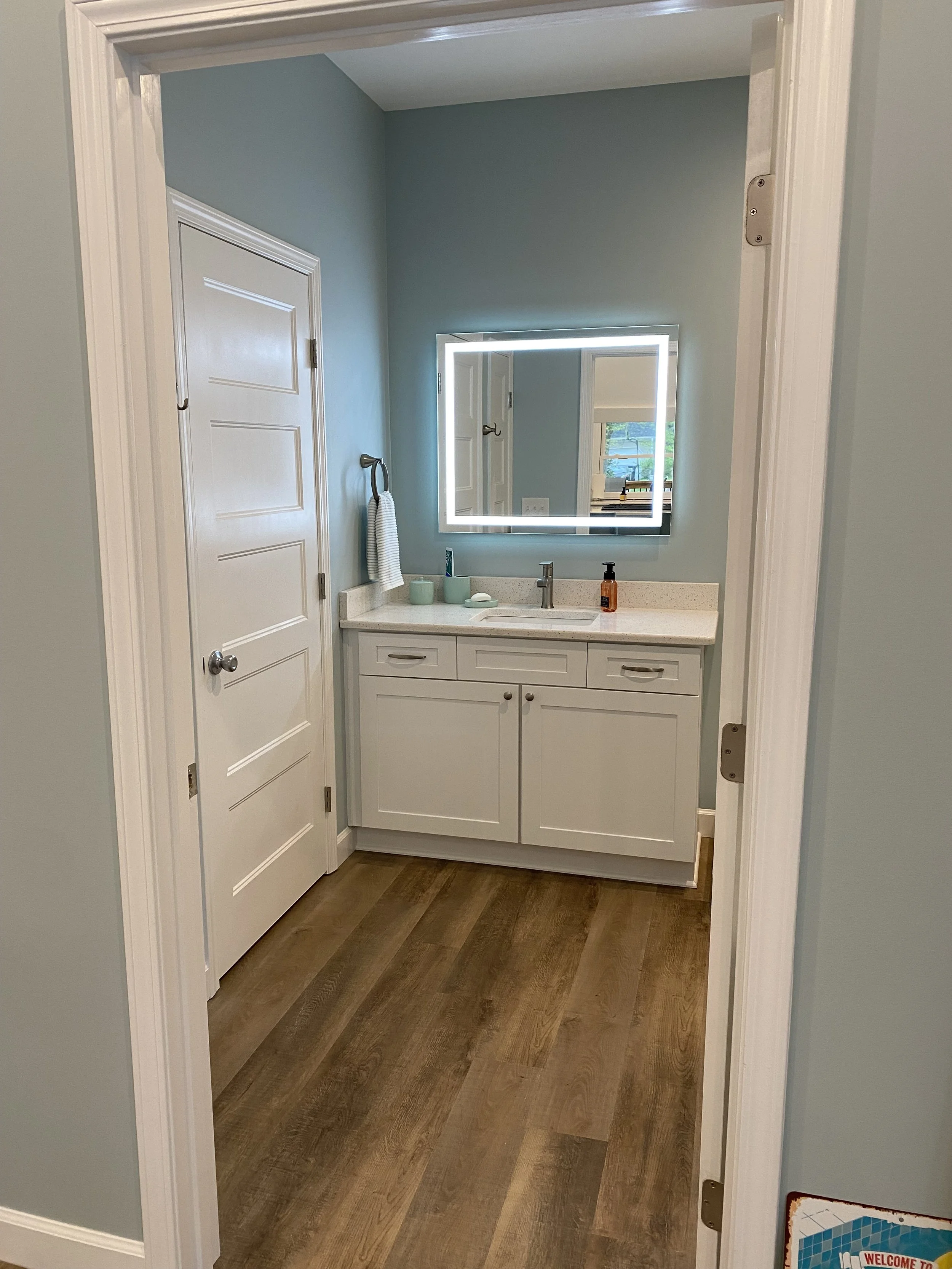 Full bathroom in detached studio apartment/pool house. LVP flooring. Semi custom vanity cabinet with Quartz top. Light up vanity mirror.