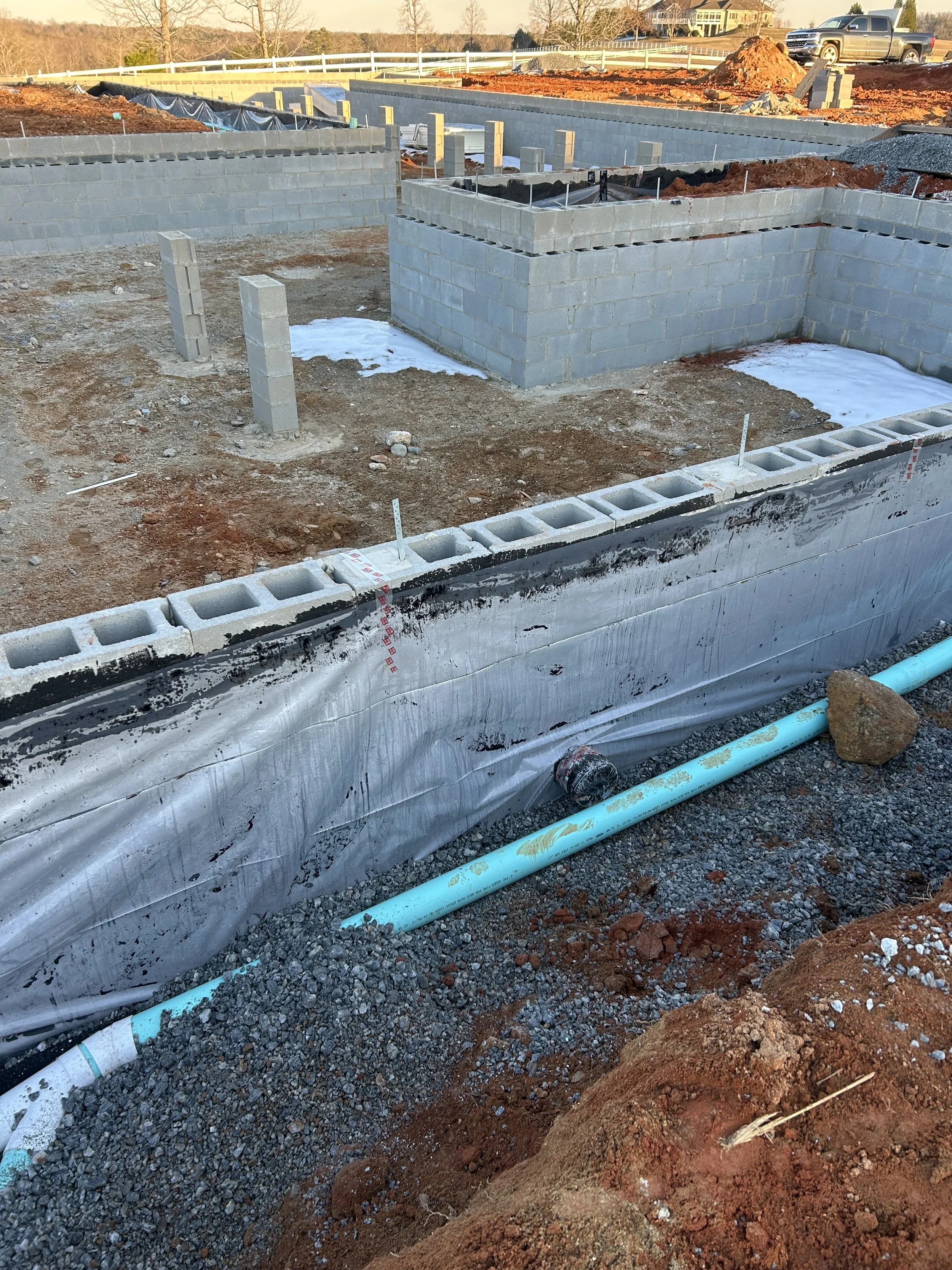 Foundation water proofing. Two coats of roll on waterproofer, 6mil poly, 4" corrugated foundation drain surrounded by washed stone gravel and slopped to designated wash out area. 4" green hard pipe run for gutter/downspout drainage to tie into in the