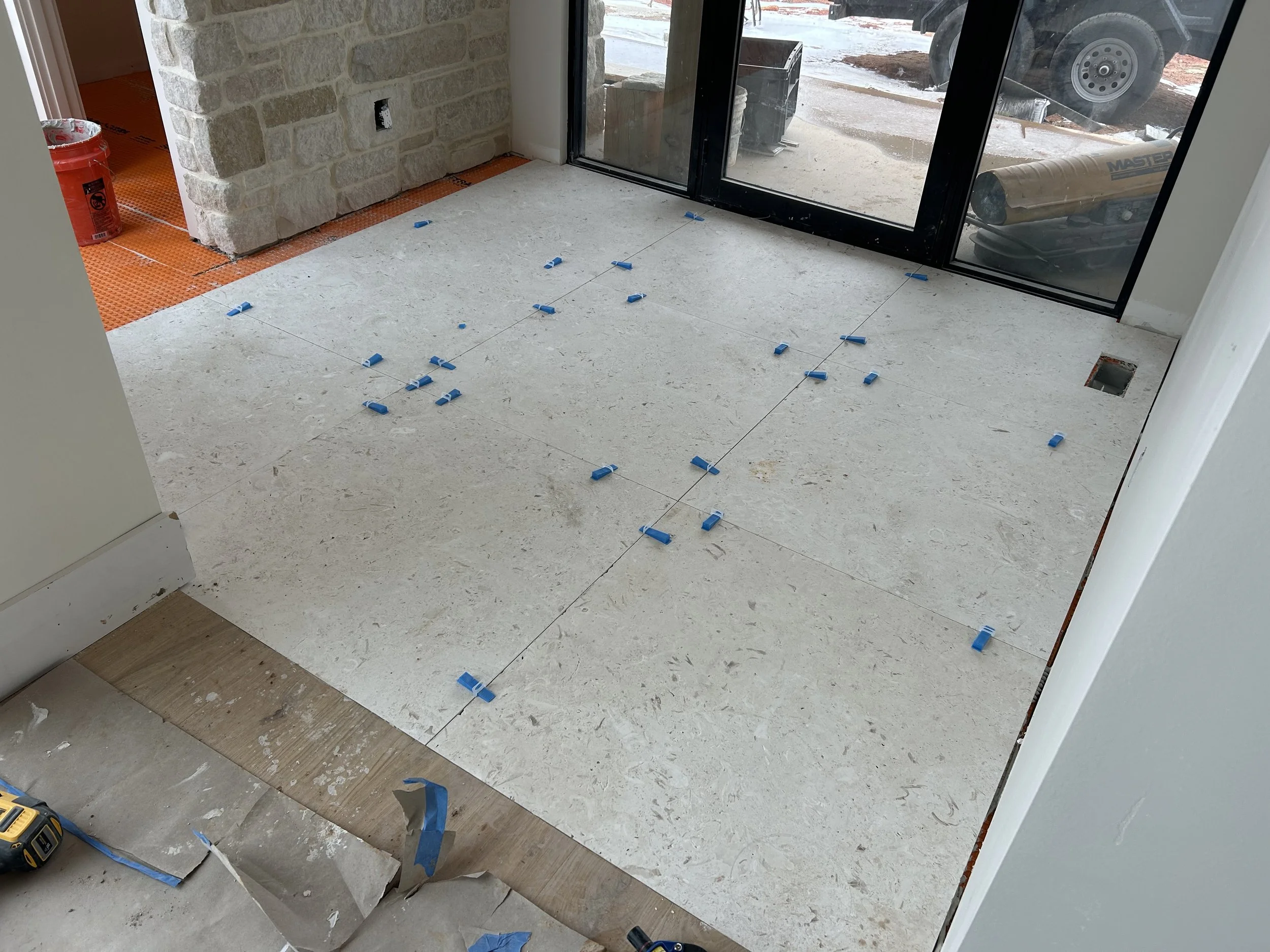 3'x3' large format real limestone tiles. Real limestone veneer stone on interior wall. Aluminum quaker door with sidelights. Floor joists were dropped in the framing process where ever thicker tile would be used. By doing this we were able to maintai