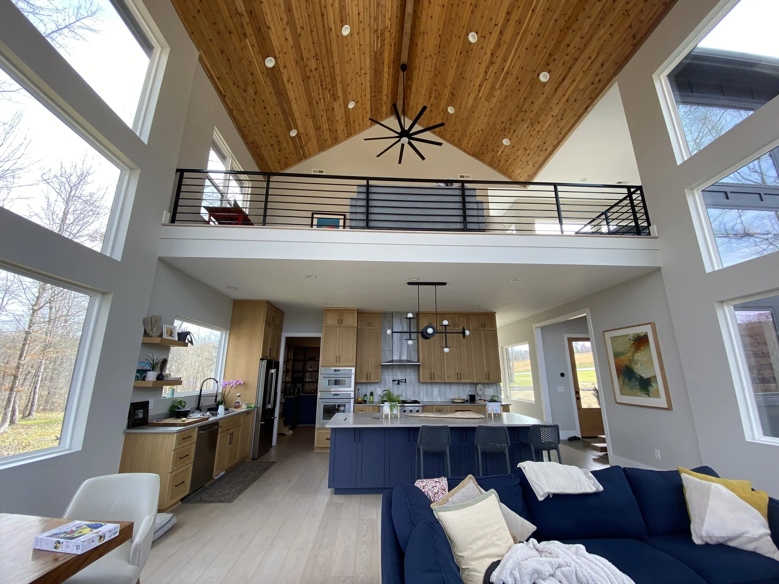 Two story living room with vaulted ceiling. Open loft with custom welded metal handrail. 1x6 cedar tongue and groove on ceiling. 