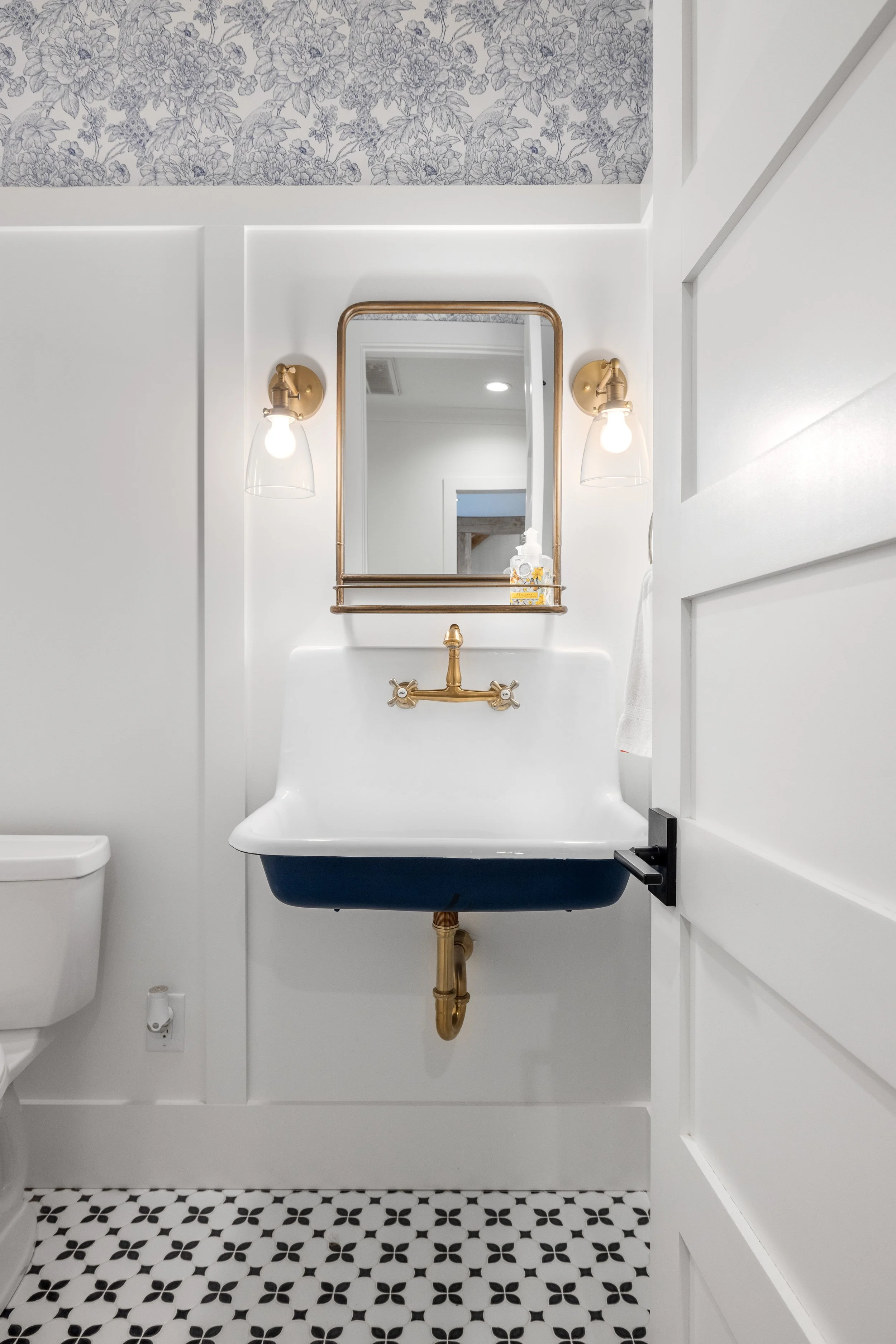 Half bath with pattern tile and a wall mount sink. 