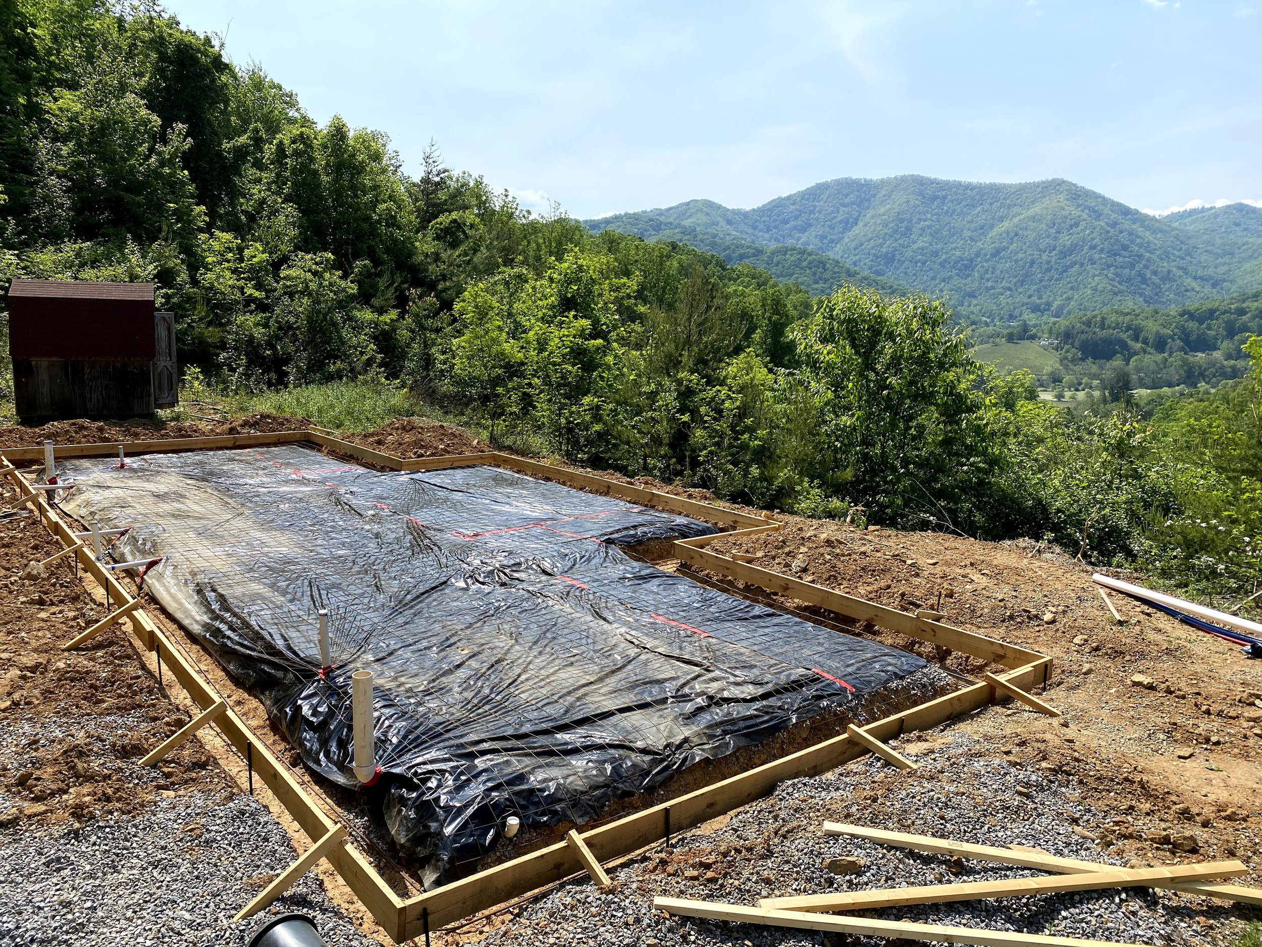Site graded, footers and foundation dug, underslab plumbing roughed in, 10mil poly, and wire mesh down and form ready for concrete.