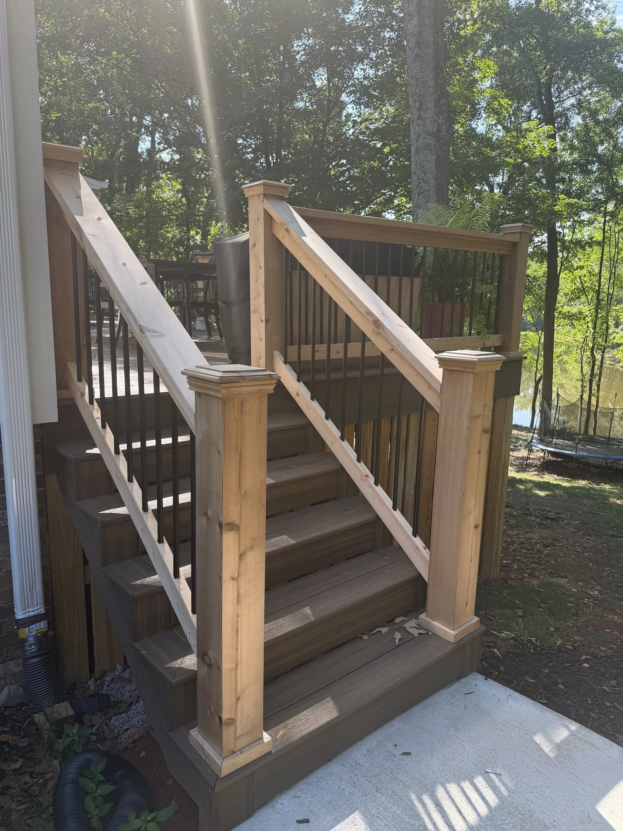 Trex Enhanced Naturals decking on stairs down to concrete sidewalk. Cedar handrails with aluminum balusters, and decorative post caps.