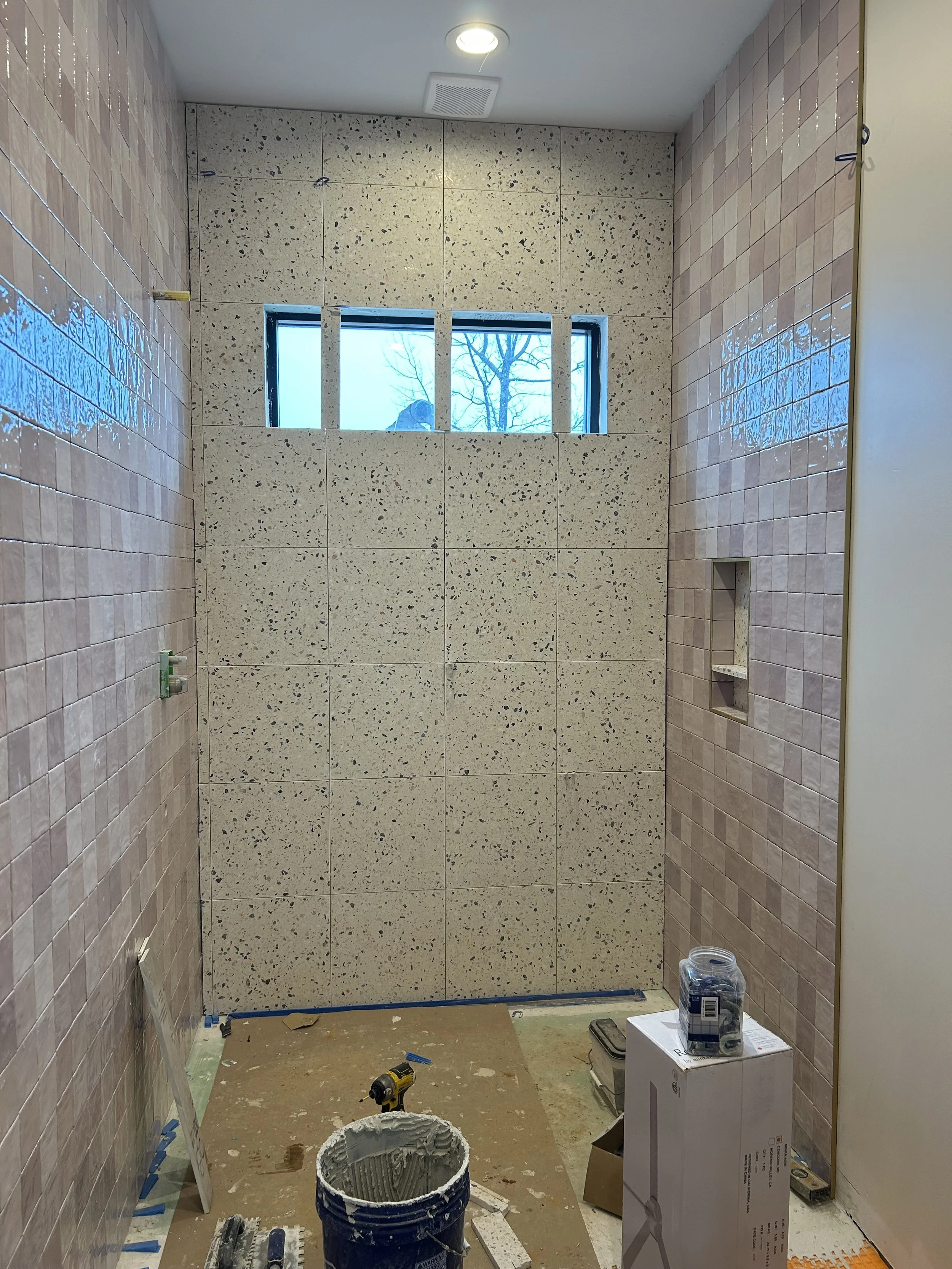 4x4 pink square tiles installed on bathroom wall to ceiling. 16"x16" real terrazzo tiles installed on floor and back wall of bathroom and shower. 