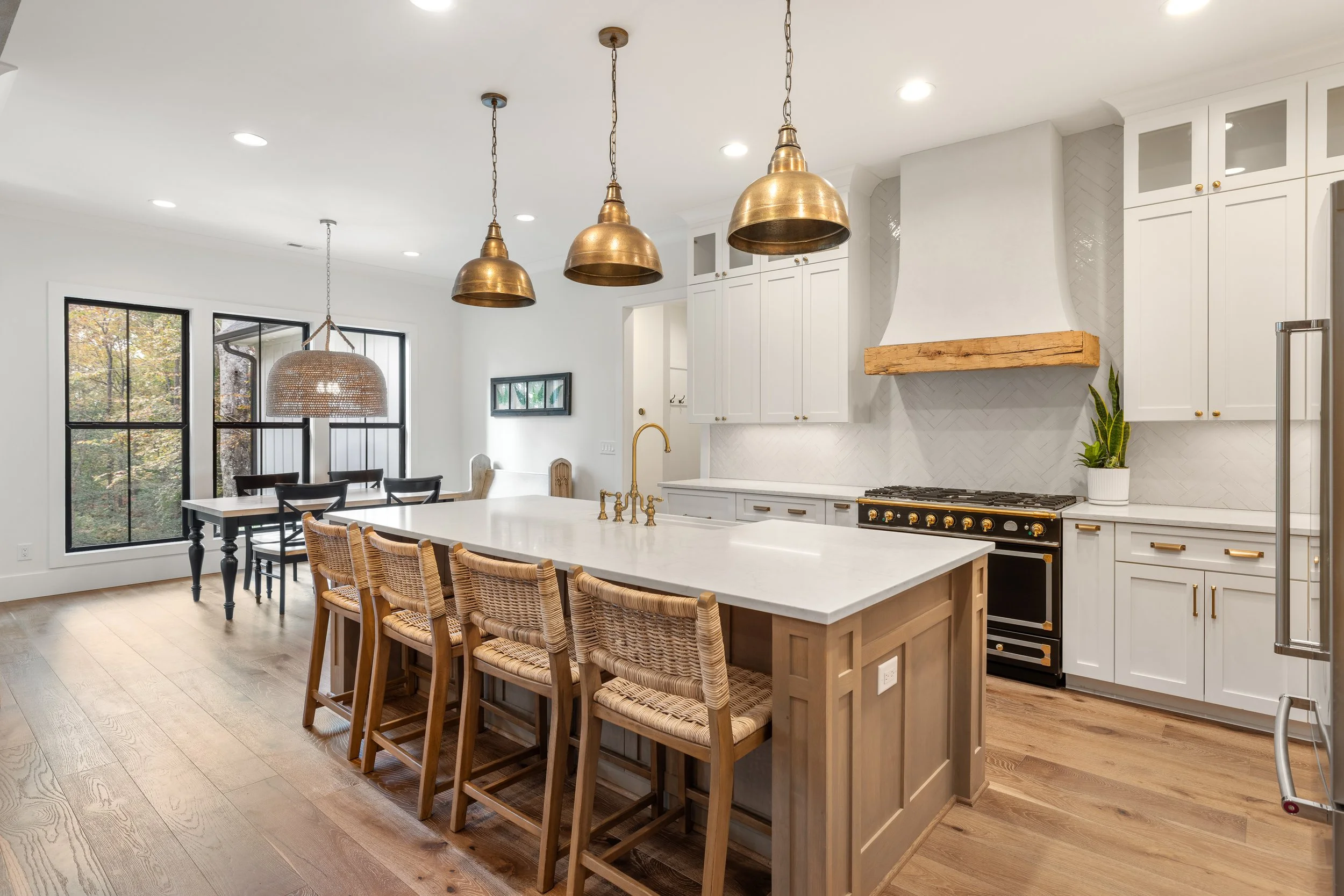 Custom cabinetry. Custom site built arched stucco coated hood vent with reclaimed wood detail. Quartz counters with tile backsplash installed on herringbone pattern.