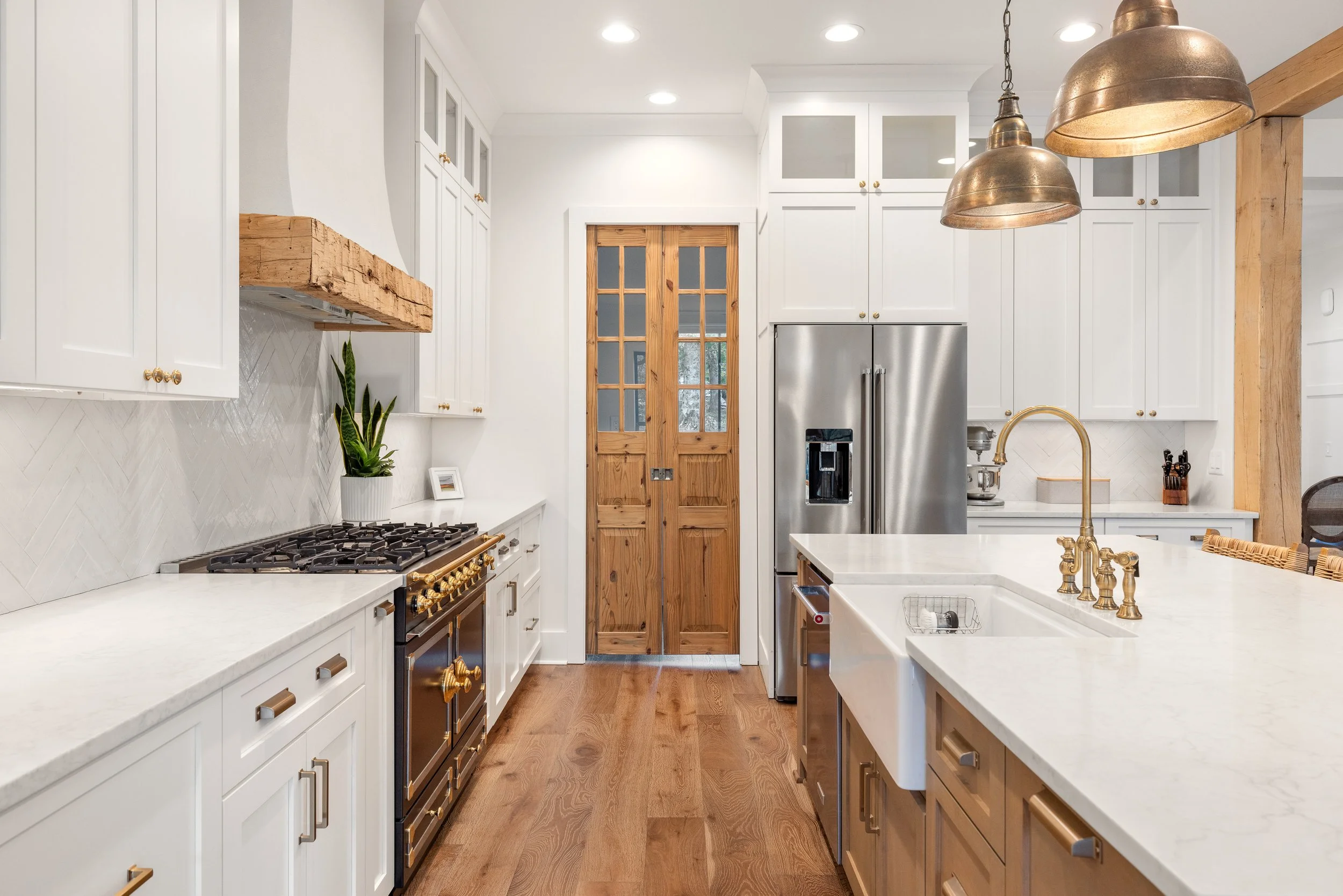 Custom cabinetry. Custom stucco hood vent with reclaimed wood detail. Quartz counters. Custom double pocket door leading into pantry.