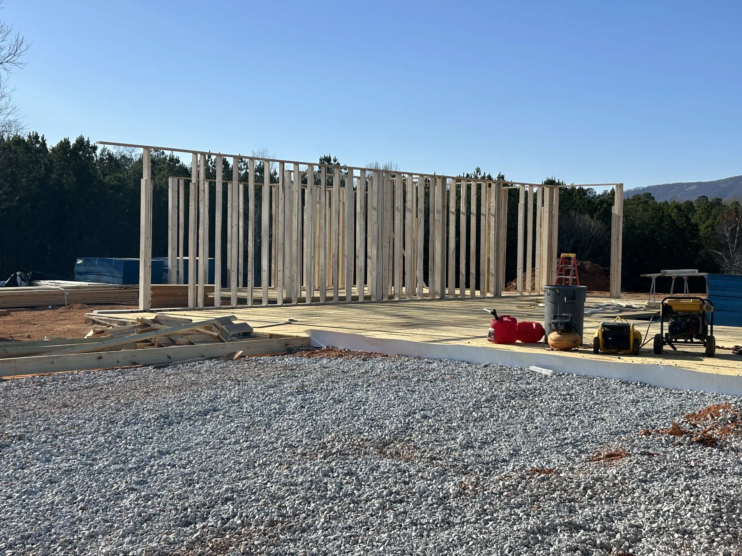 Washed stone is added to interior of garage form. Area is compacted, and wire mesh is added. 10mil poly goes over gravel. PVC flashing is added as a barrier between wood floor framing and soon to be poured concrete in garage.
