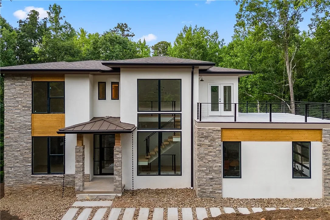Stone veneer, stucco, and cedar tongue and groove accent siding. Large vinyl windows. Shallow hip roof.