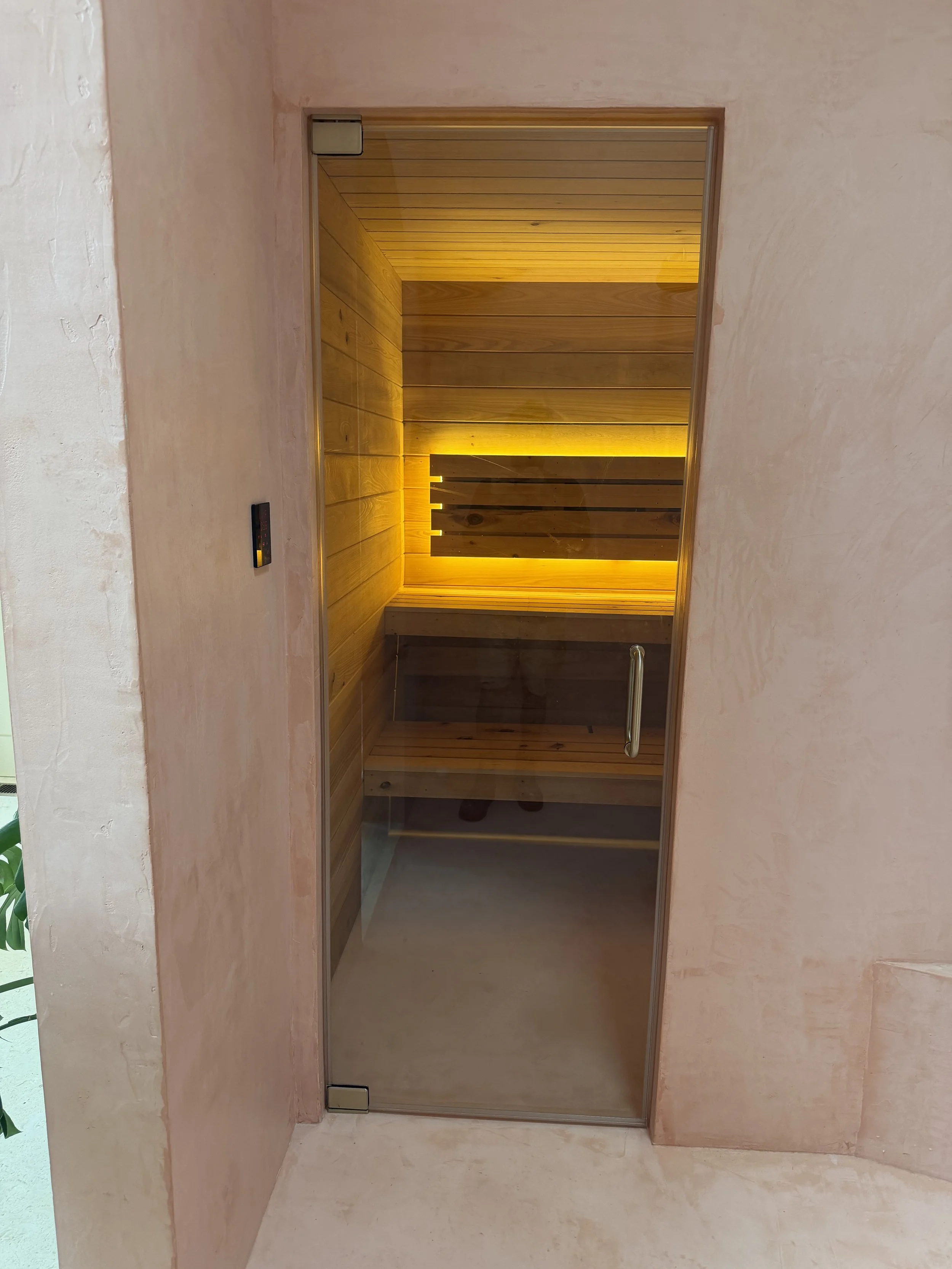 Custom hidden sauna room accessed from custom micro cement shower. Frameless glass entry door.
