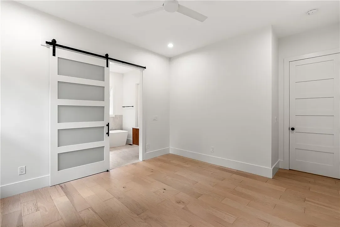 8' Tall frosted glass sliding barn door leading to primary bathroom. Wide plank LVP flooring. 