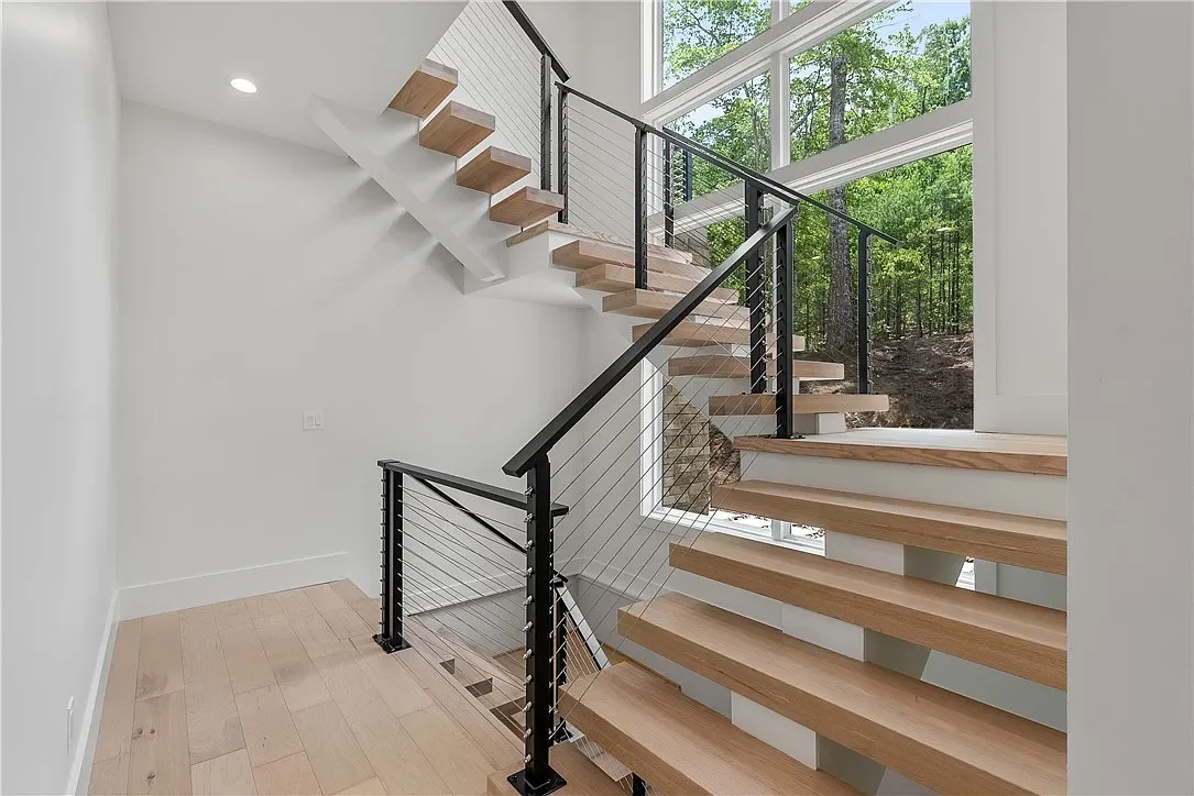 Custom floating stairs with floating landings from basement to second floor. Aluminum cable railing. 4x12 solid red oak stair treads on a custom built mono stringer.