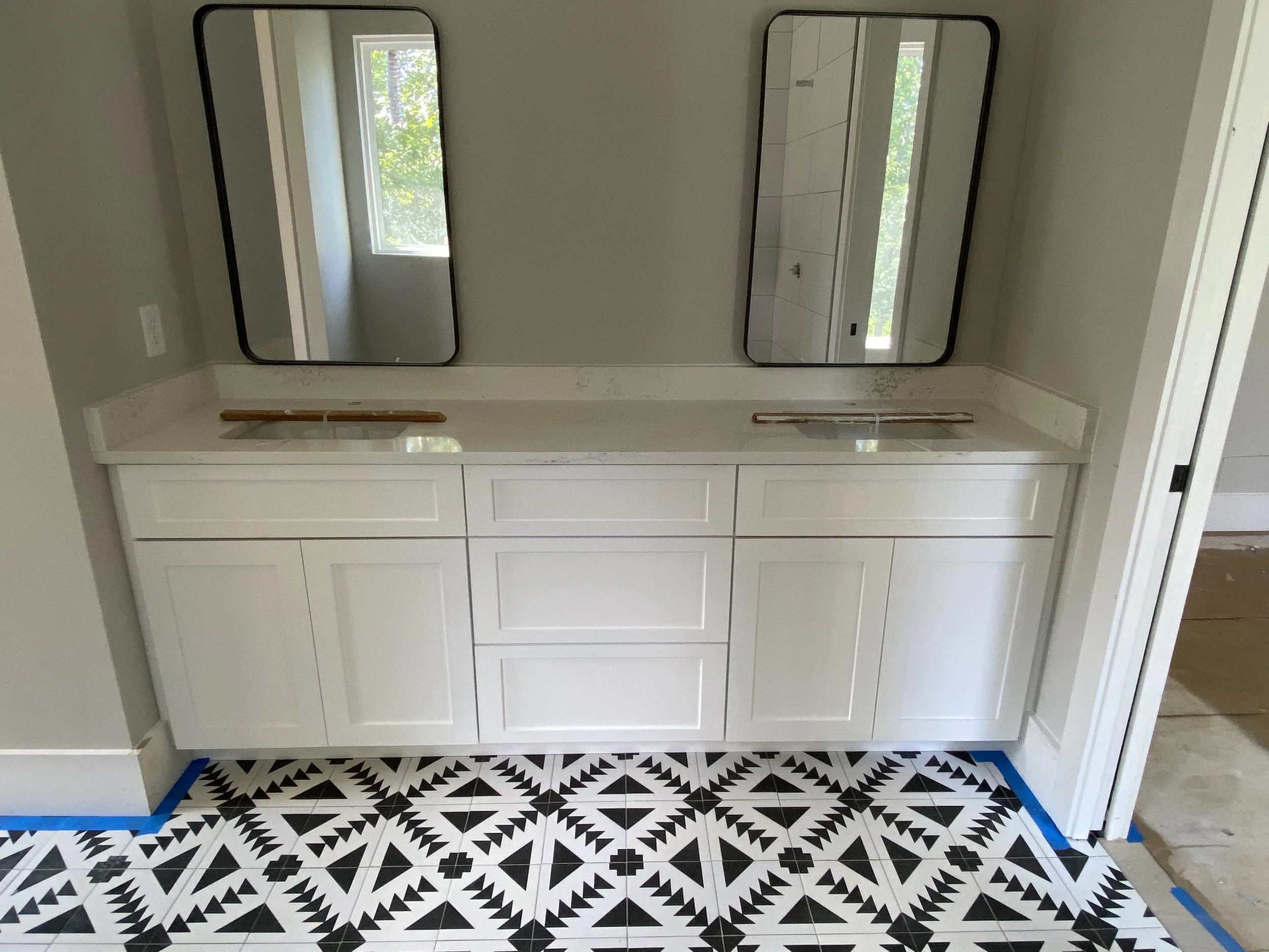 Custom double vanity with Quartz top and decorative patterned floor tile.