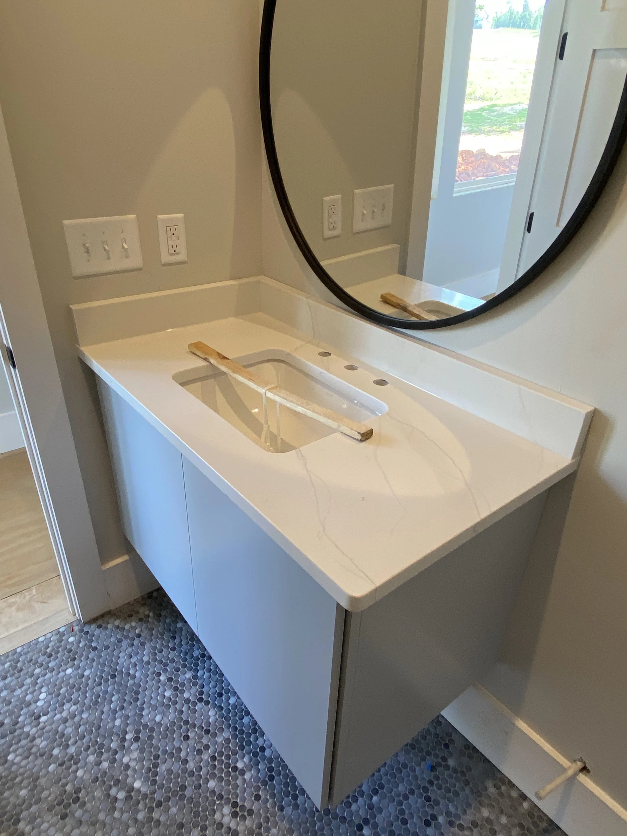 Custom floating vanity with Quartz top. Penny tile on floor. Engineered hardwoods throughout house.