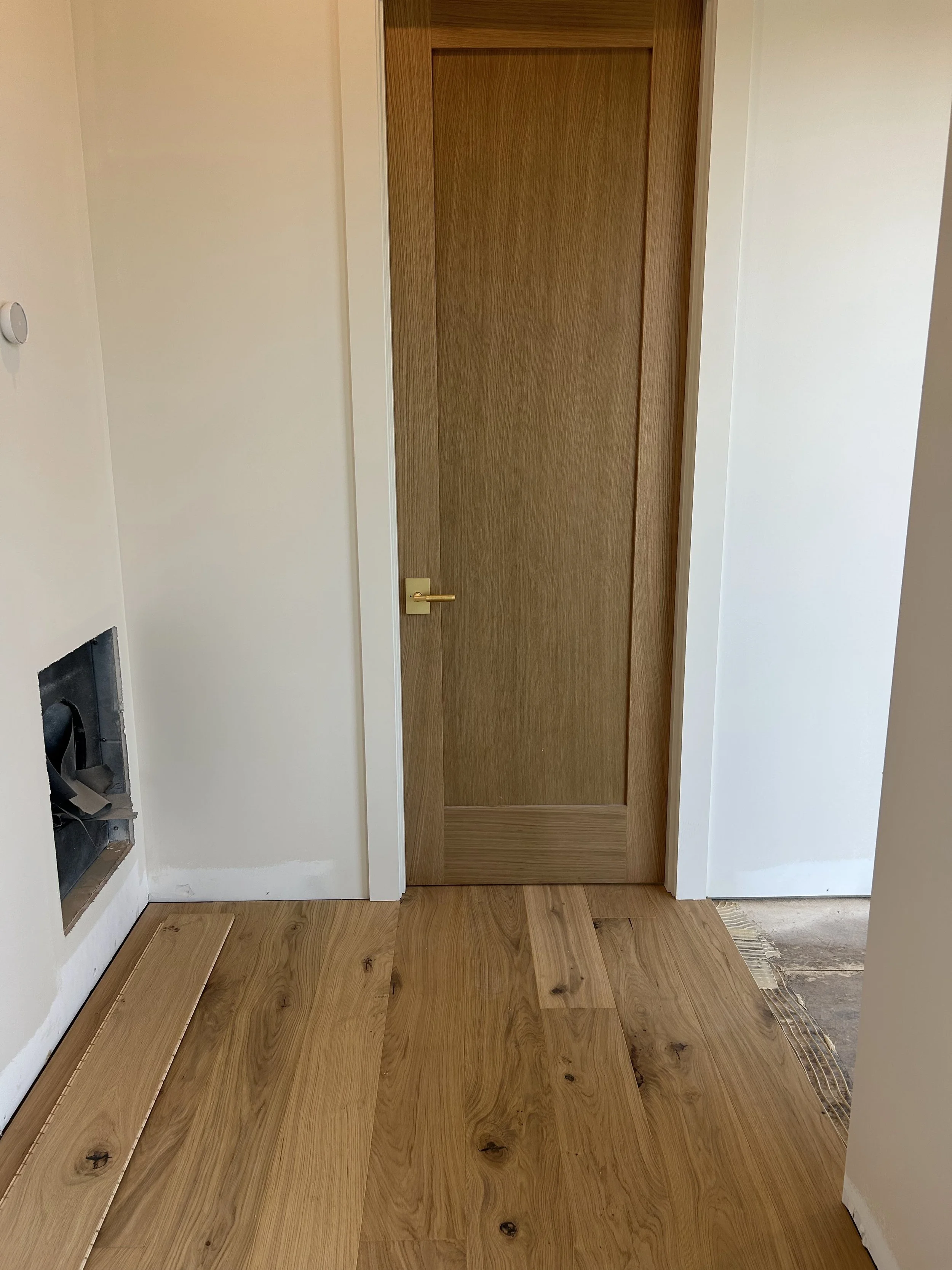 8' tall solid white oak interior doors with brushed gold lever handles. 8" wide engineered glue down white oak flooring.