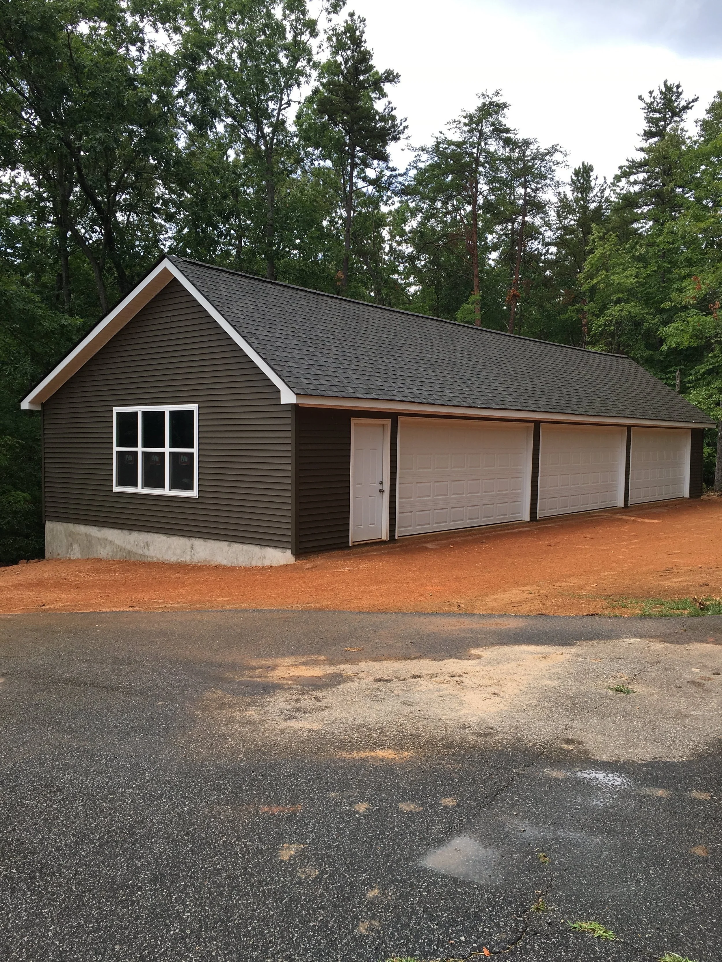 Large detached garage with vinyl siding and asphalt shingle roof.