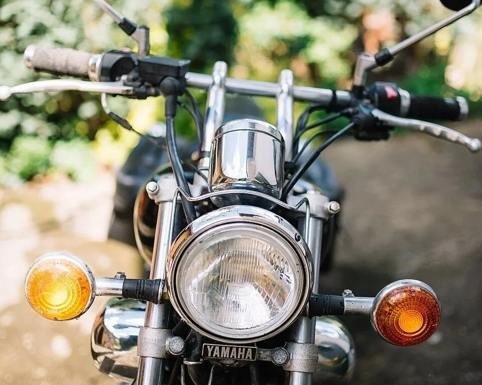 Front detail of a custom motorcycle with headlamp, handlebars and front fork.