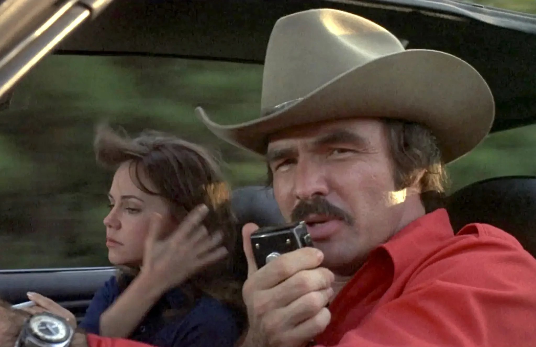 Burt Reynolds using a CB radio alongside Sally Field in the 1977 movie “Smokey and the Bandit.”
