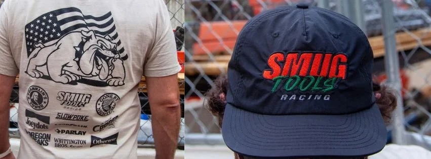 Parlay capsule collab tee with bulldog and flag graphic, next to a navy SMUG TOOLS Racing cap