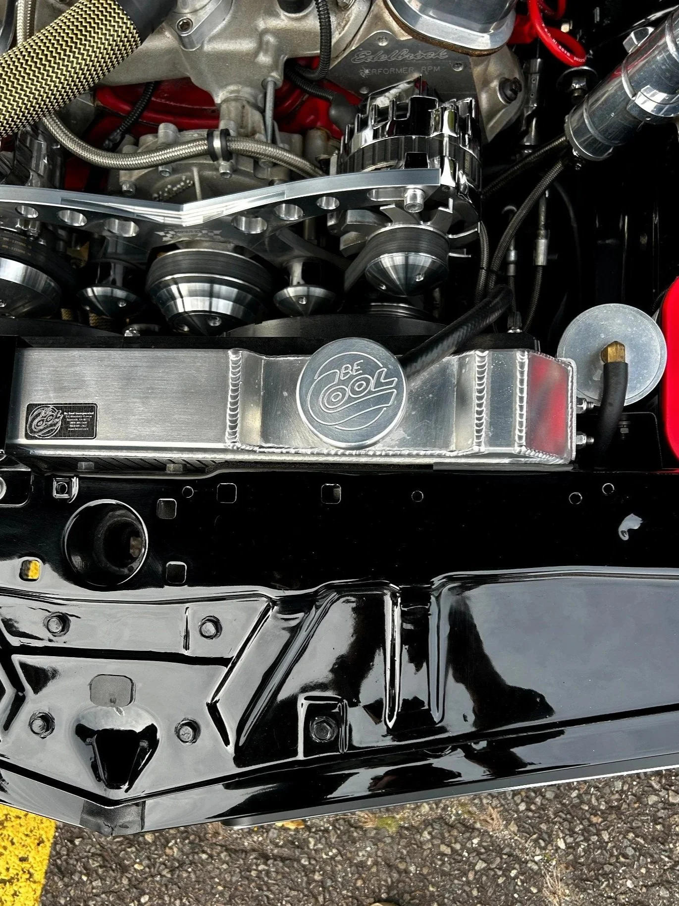 Polished aluminum Be Cool radiator and billet accessory drive in a detailed engine bay, with a glossy black core support below.