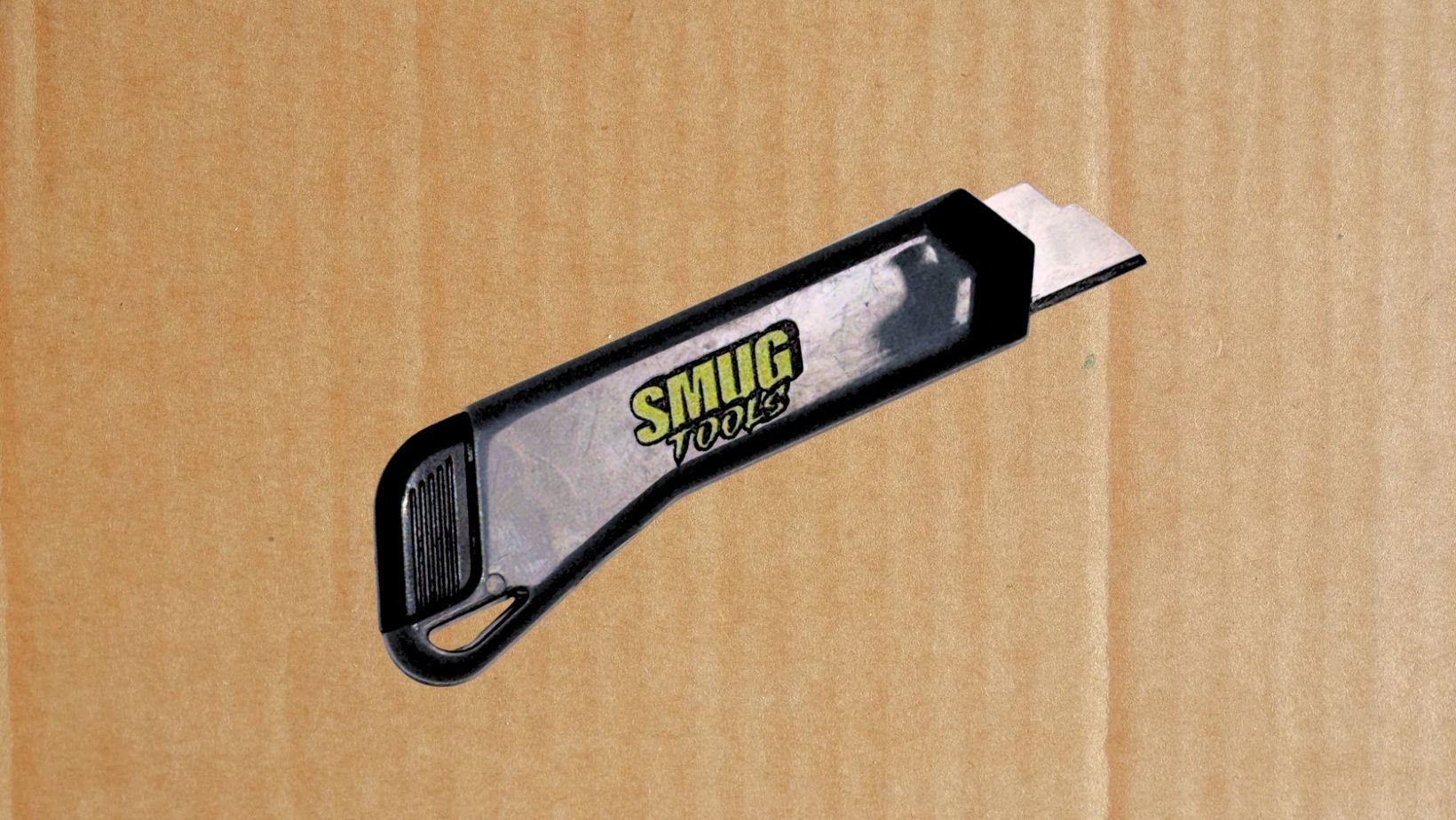 smug tools mini box cutter against cardboard background