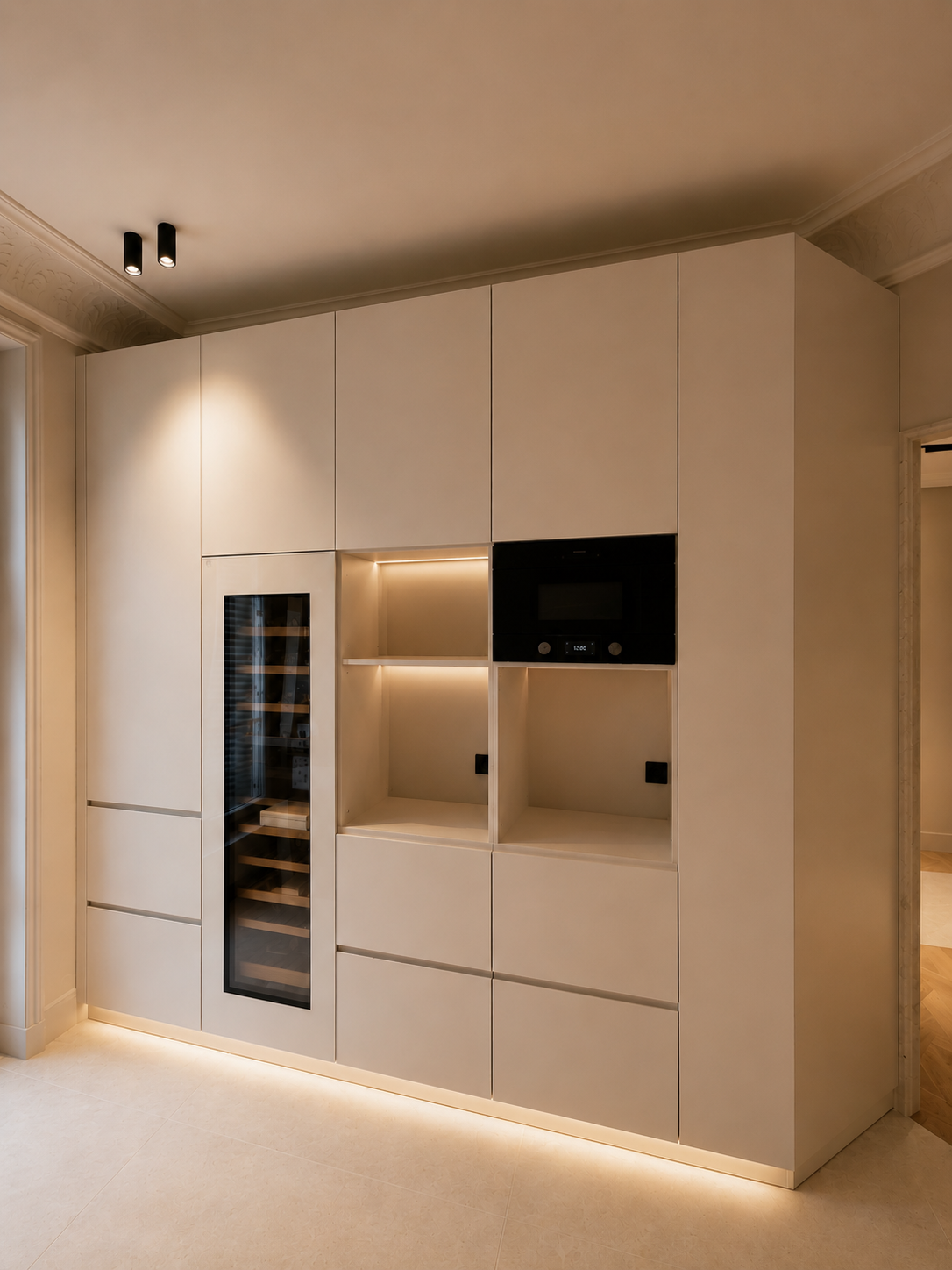 Mur de cuisine moderne avec armoires blanches, un garde-vin en verre noir, un micro-ondes noir intégré, et un éclairage LED au sol.