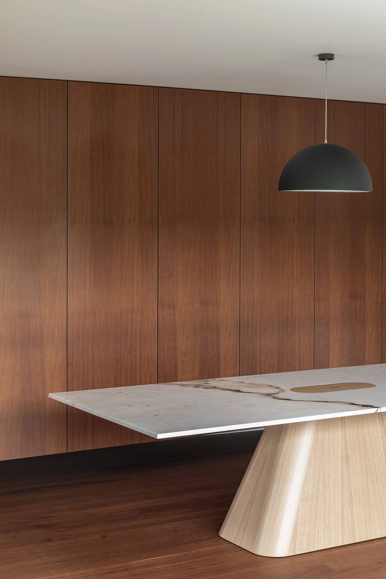 Un mur en bois avec une table en marbre blanc et un éclairage suspendu noir dans une pièce moderne