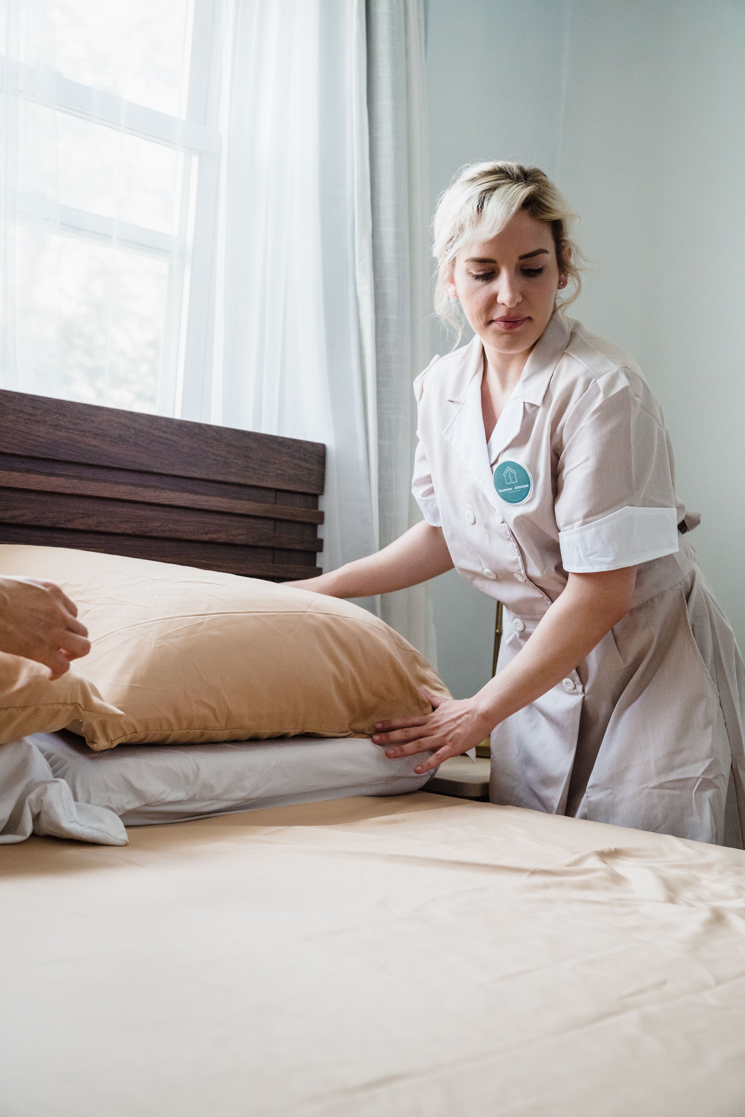 Home healthcare worker in uniform changing bedding on a patient's bed