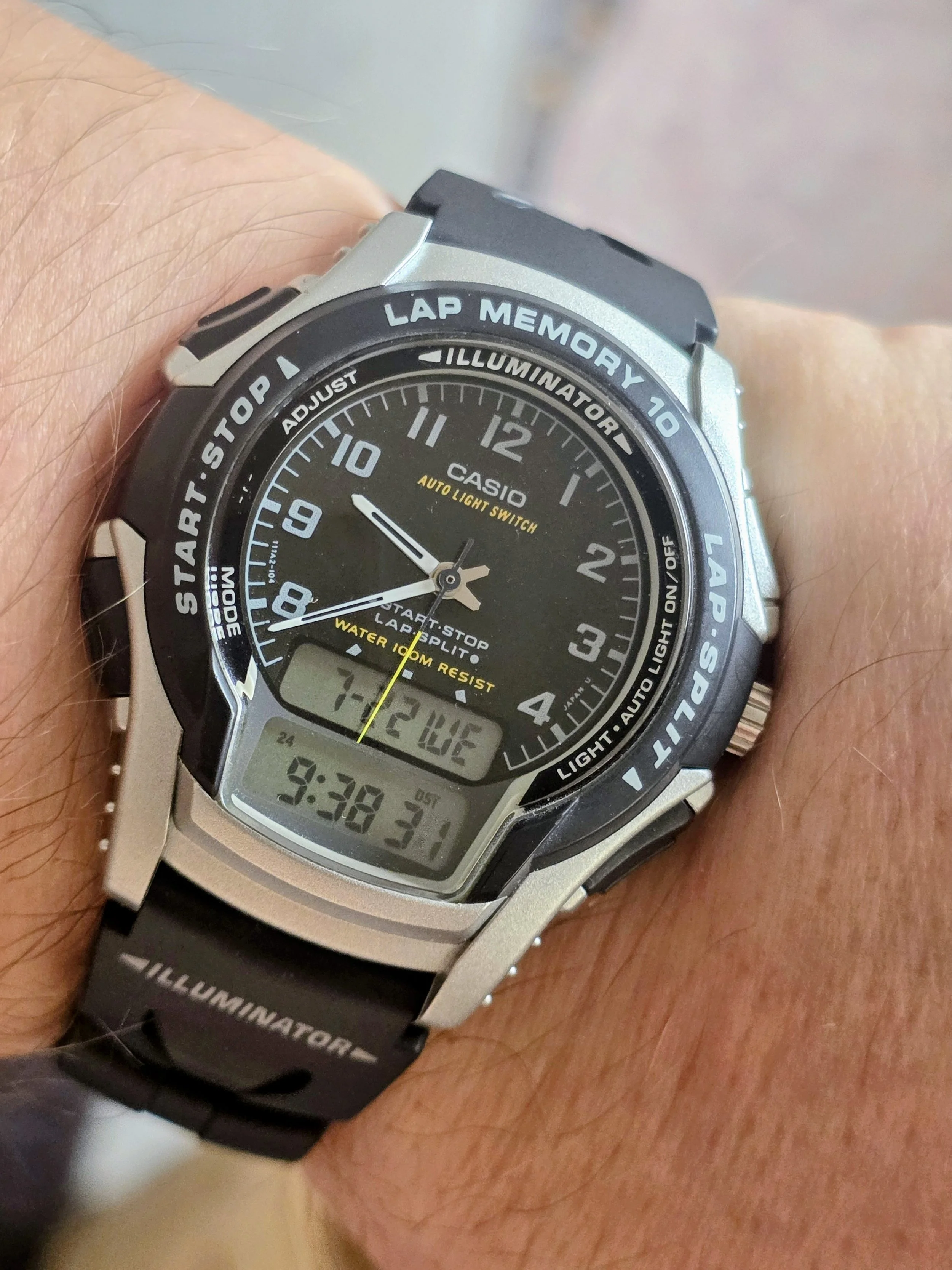 Close-up of a person's wrist wearing a Casio digital and analog watch with a black strap, displaying time, date, and various functions.