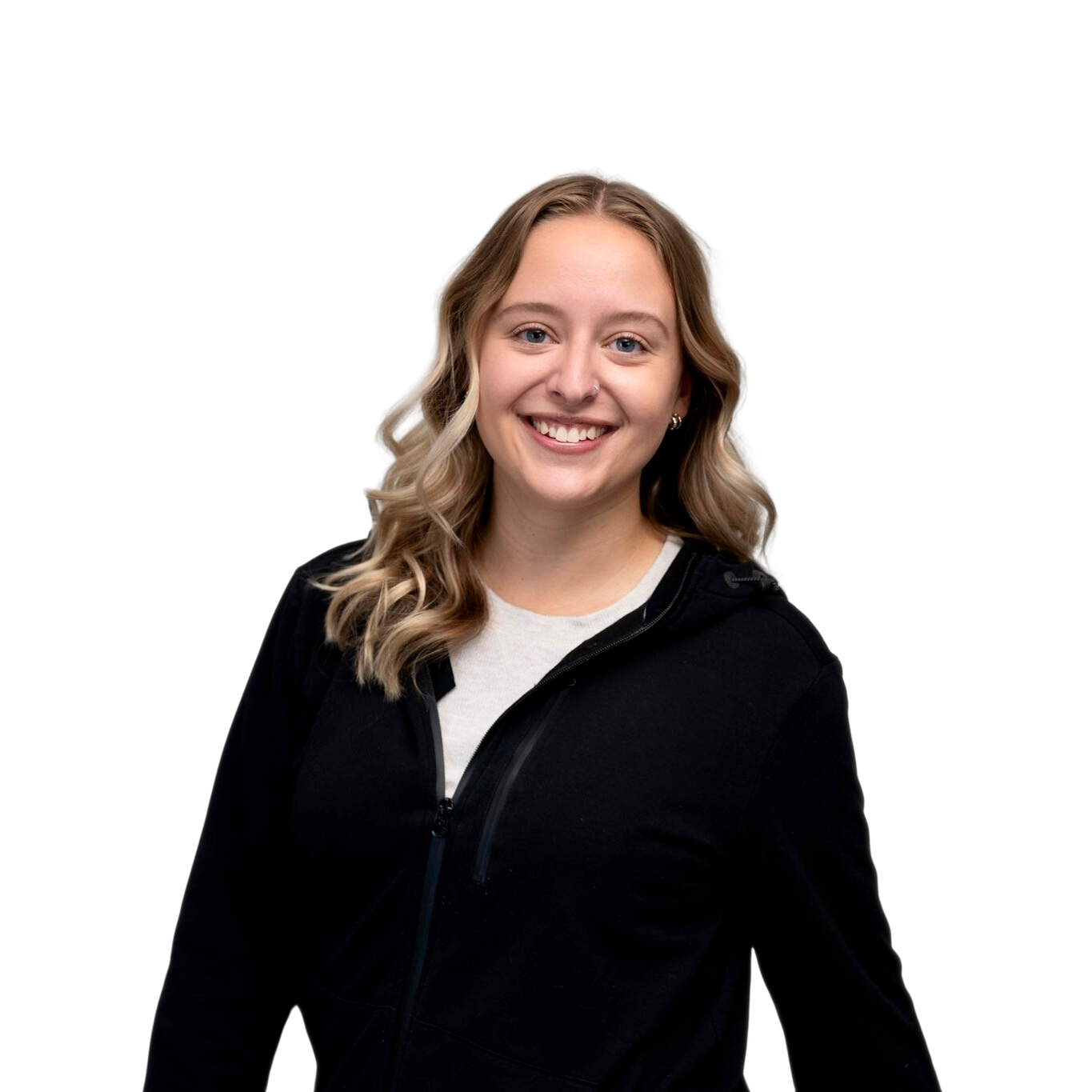 Portrait of a young woman with wavy blonde hair, blue eyes, smiling, wearing a black jacket and a white shirt, against a white background.