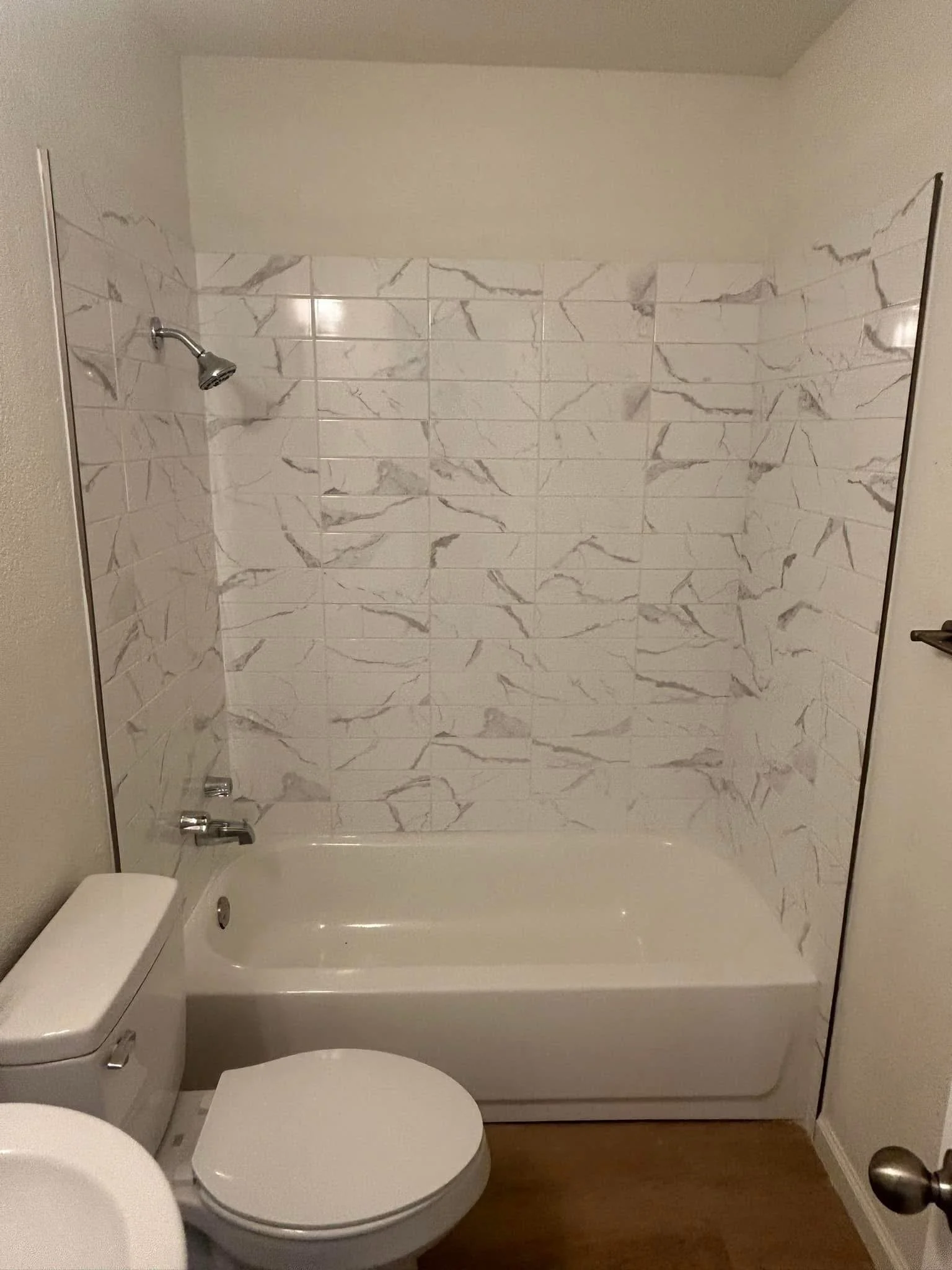 Bathroom with a bathtub, a toilet, and a marble-tiled shower area.