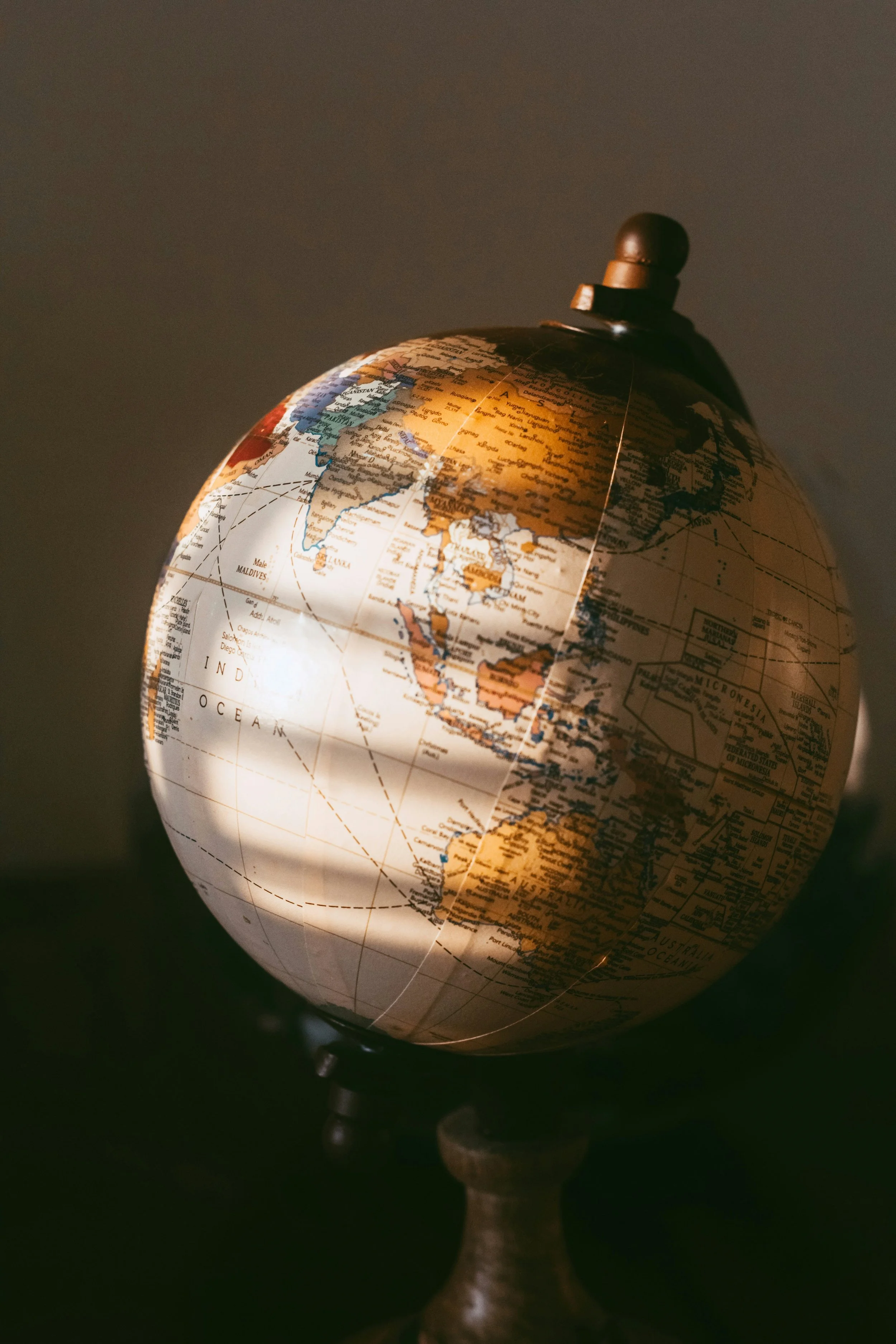 A globe illuminated by a light source, showing continents and countries with visible text, mounted on a stand.
