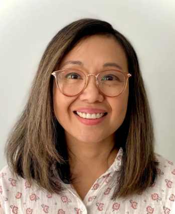 A woman with shoulder-length brown hair, glasses, and a floral button-up shirt smiling at the camera.